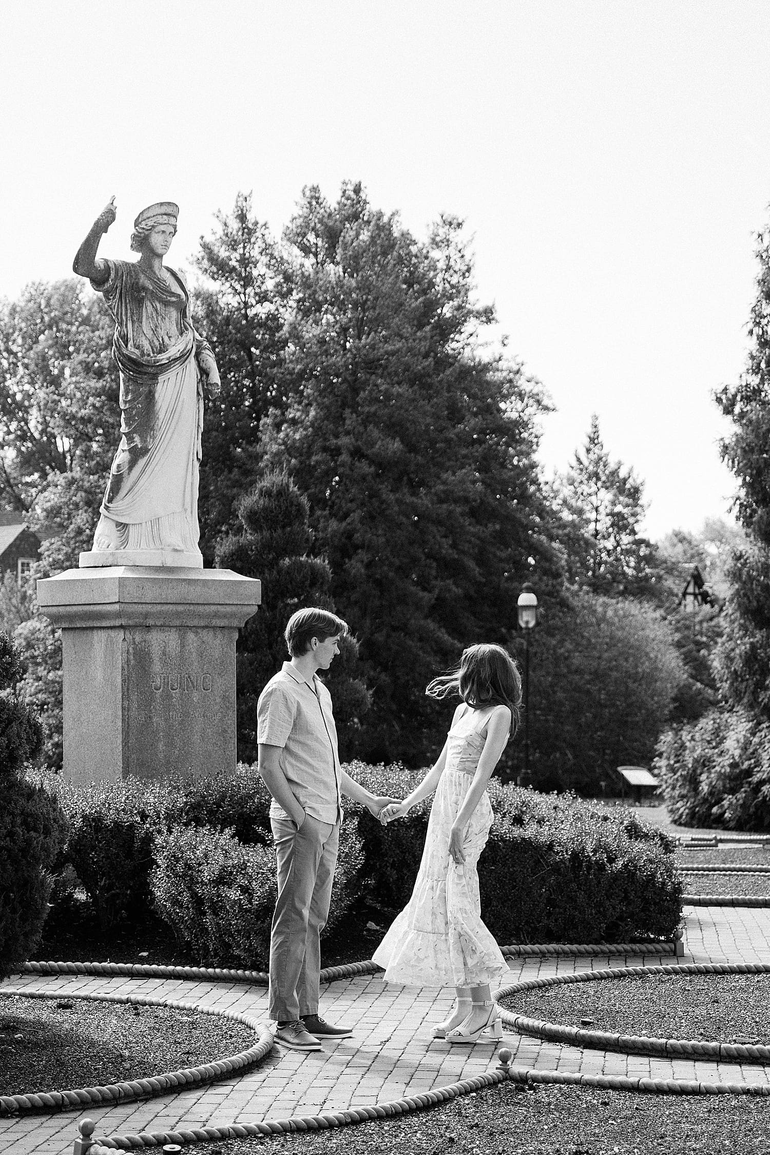bride and groom to be stand under big statue for wandering session