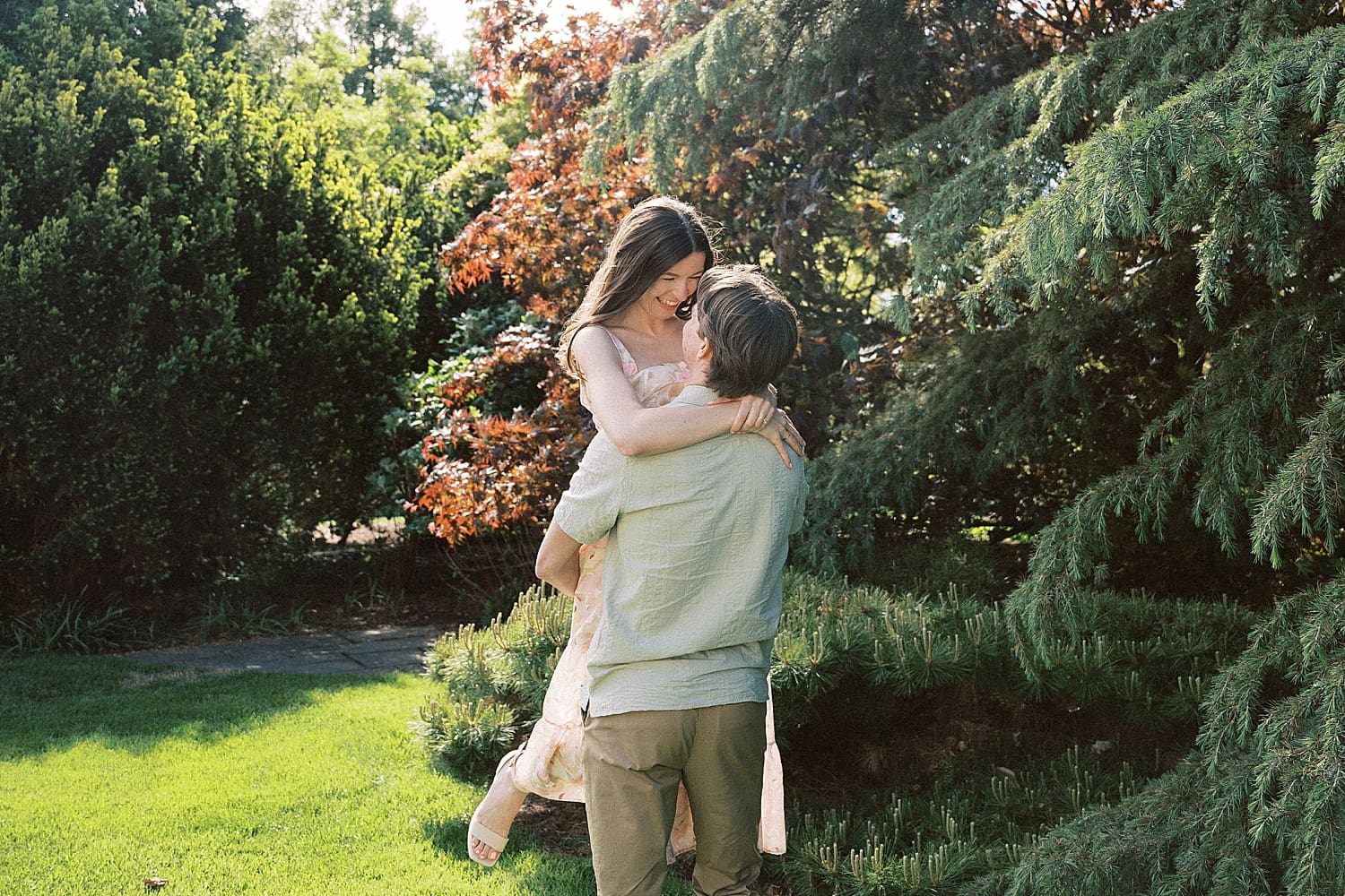 man lifts his bride-to-be up for a spin in garden by St. Louis wedding Photographer