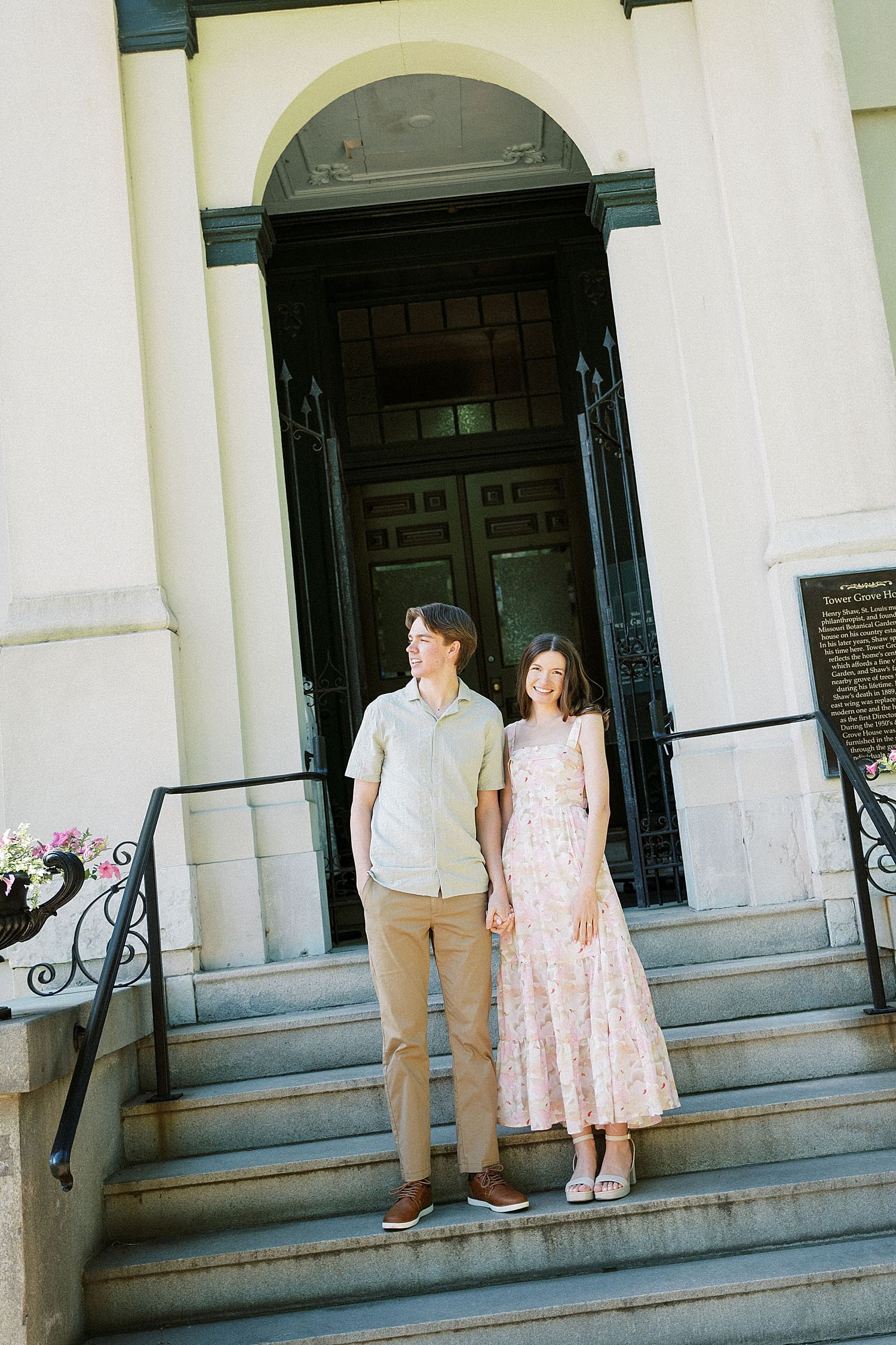brunette couple stand on stairs leading up to ornate building by Camille Meers Photography 