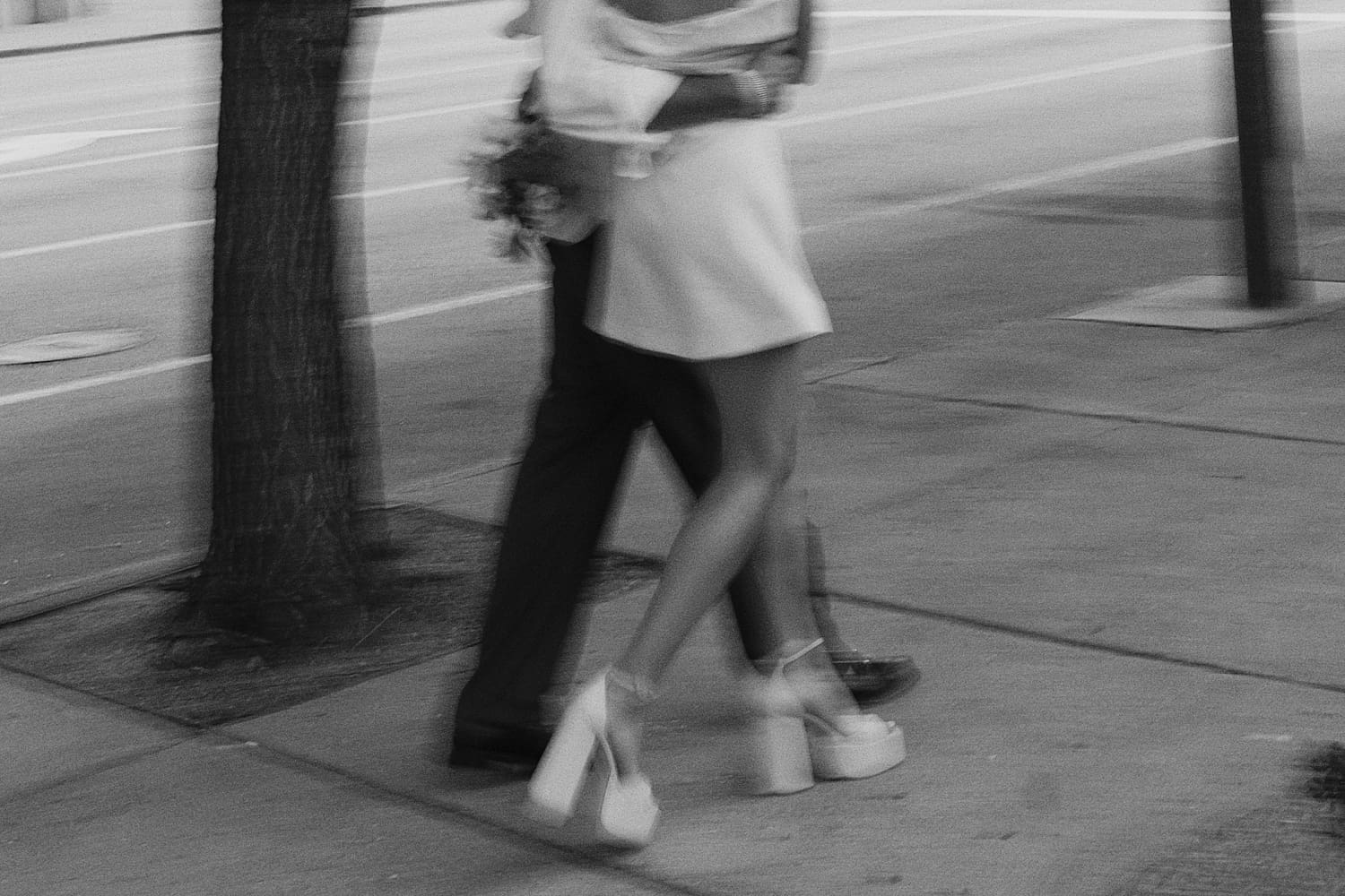 newlyweds walk arm in arm down the sidewalk by St. Louis Wedding Photographer