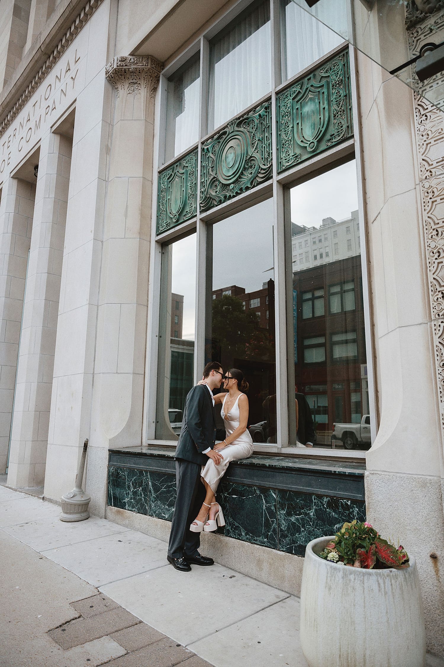 woman sits in windowsill while man leans in for a kiss by Camille Meers Photography