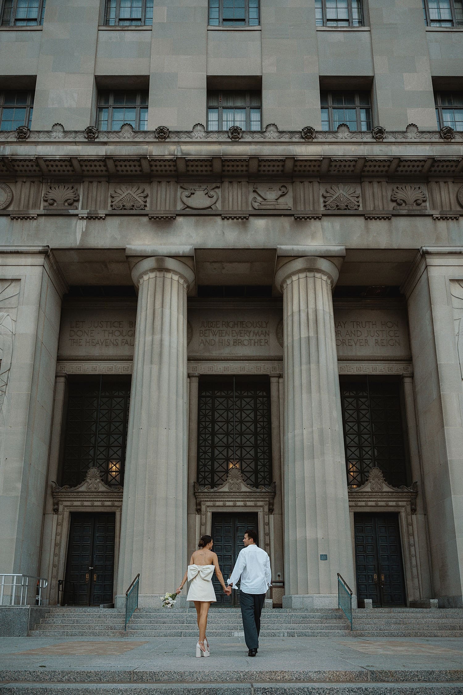 newlyweds walking up steps in front of columns for editorial elopement session