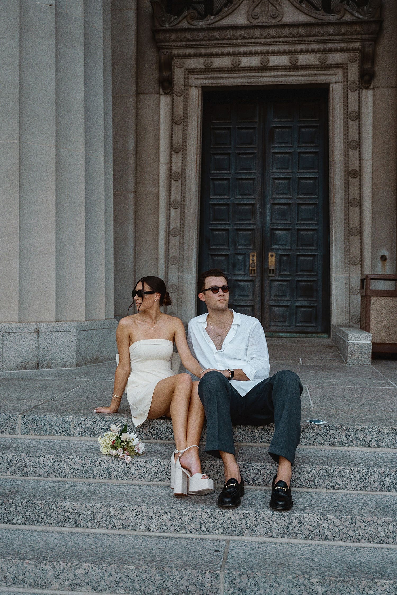 newlyweds wear sunglasses and sit on courthouse steps by Camille Meers Photography