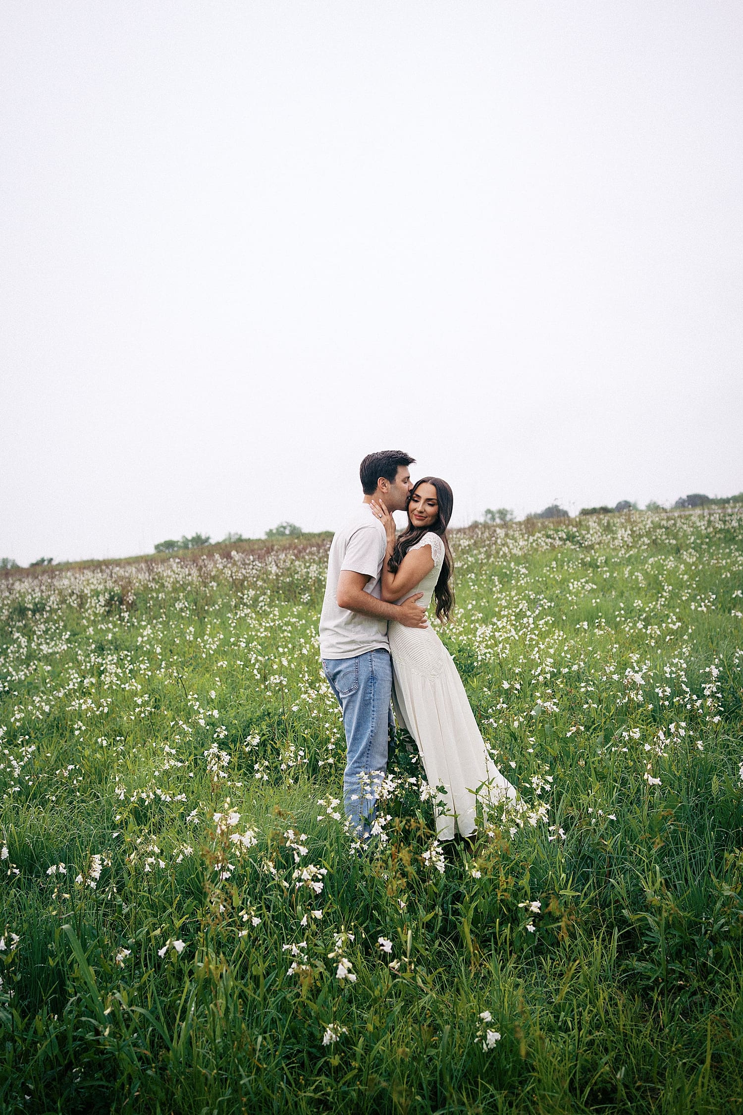 couple kisses in flowers learning what if it rains on your engagement session