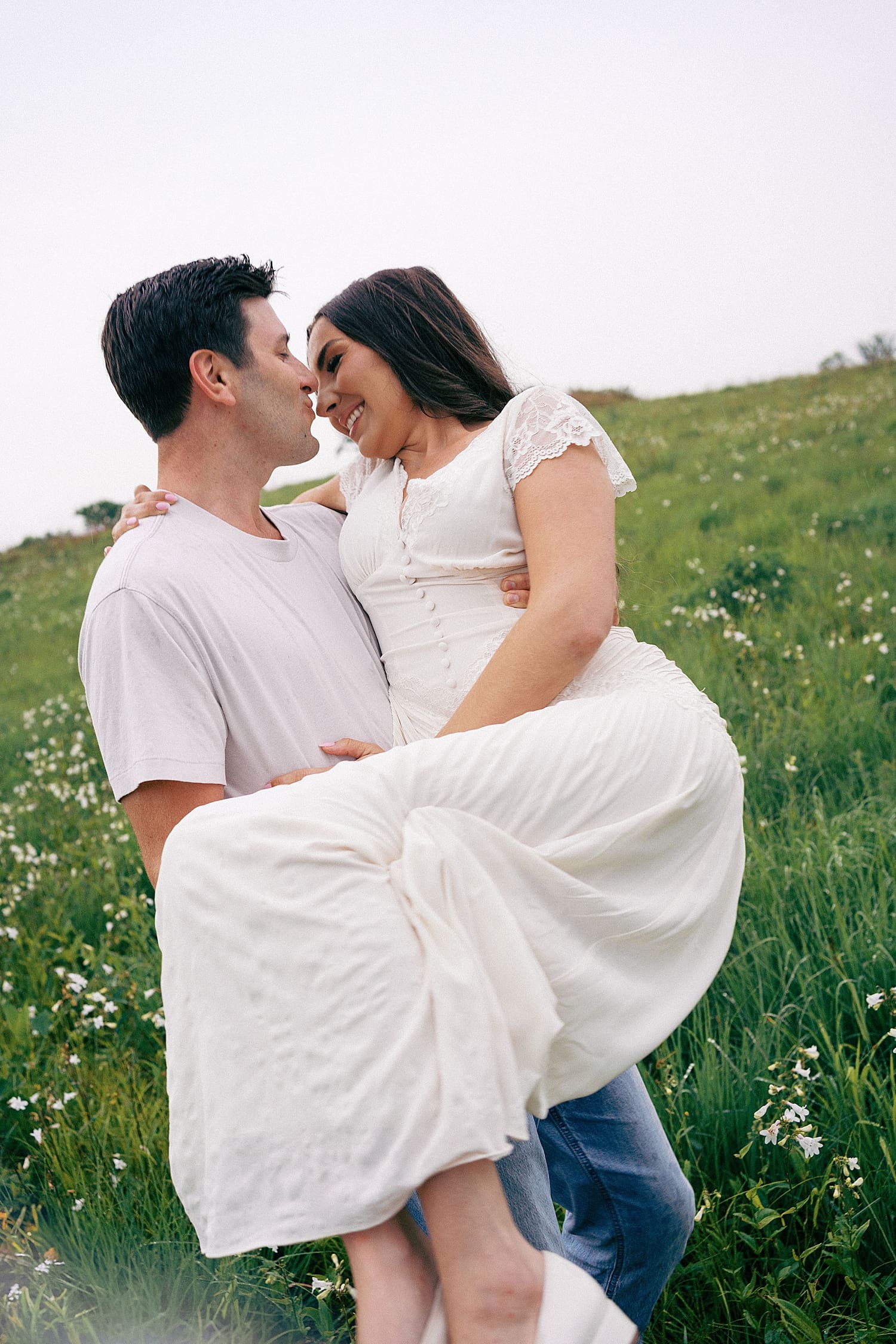 husband-to-be lifts up woman in white vintage dress by Camille Meers Photography