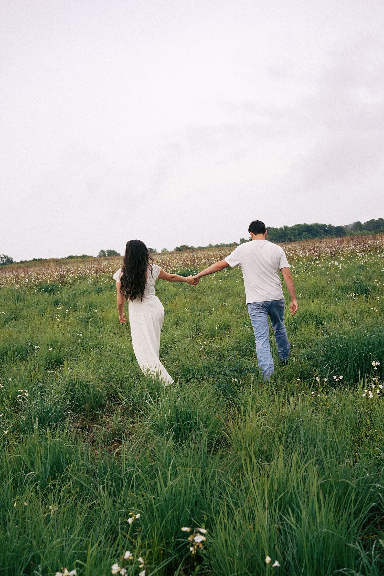 two people walk hand in hand through feeling thinking about what if it rains on your engagement session