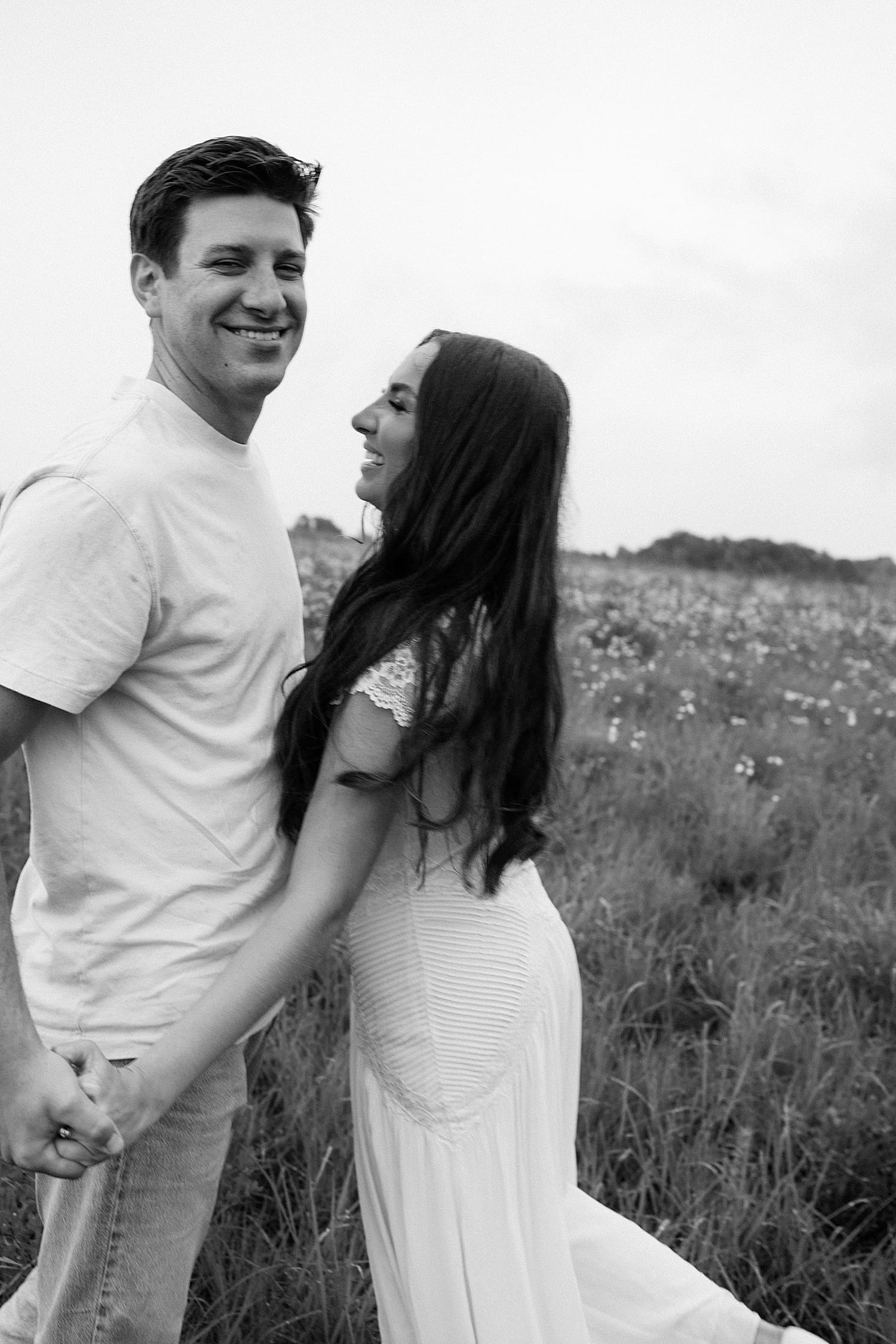 couple laughs together in big landscape of wildflowers by St. Louis wedding photographer