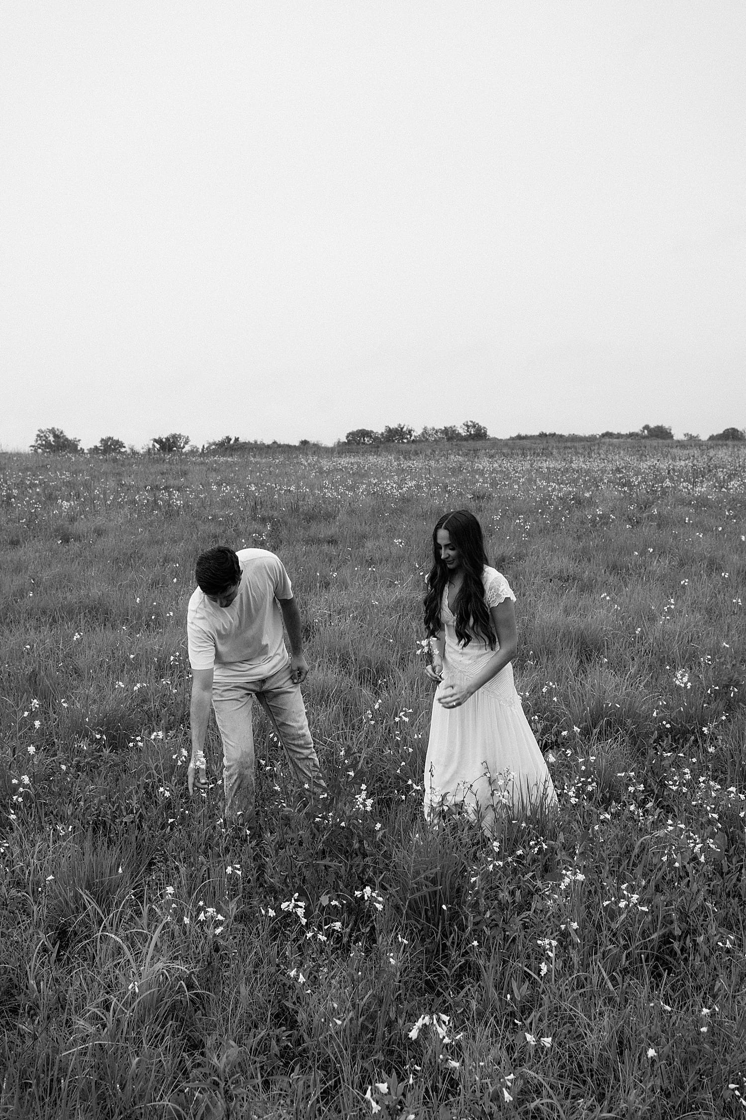 man picks wildflowers for his wife-to-be by Camille Meers Photography