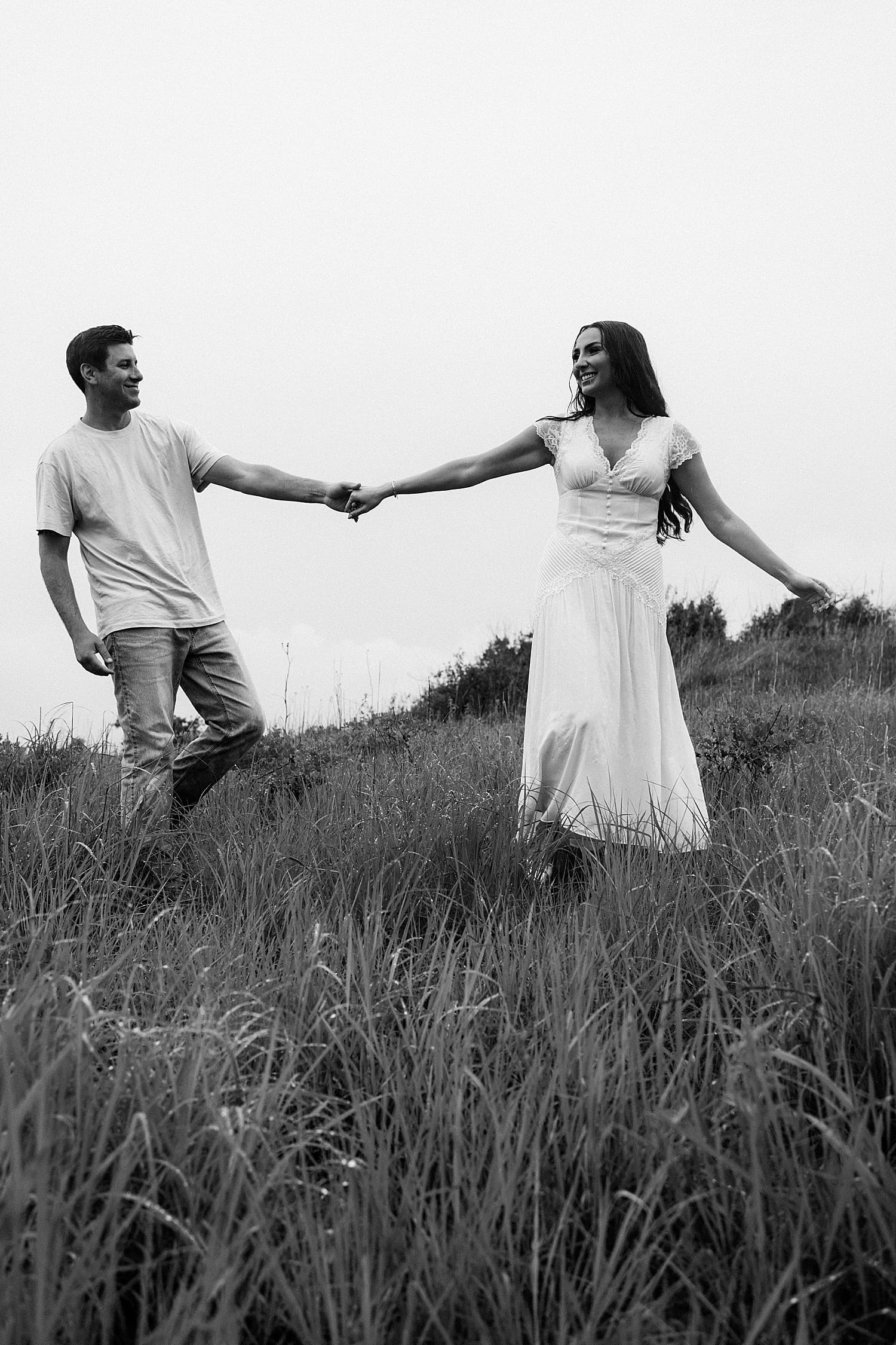 two people hold hands and spin in the field by Camille Meers Photography