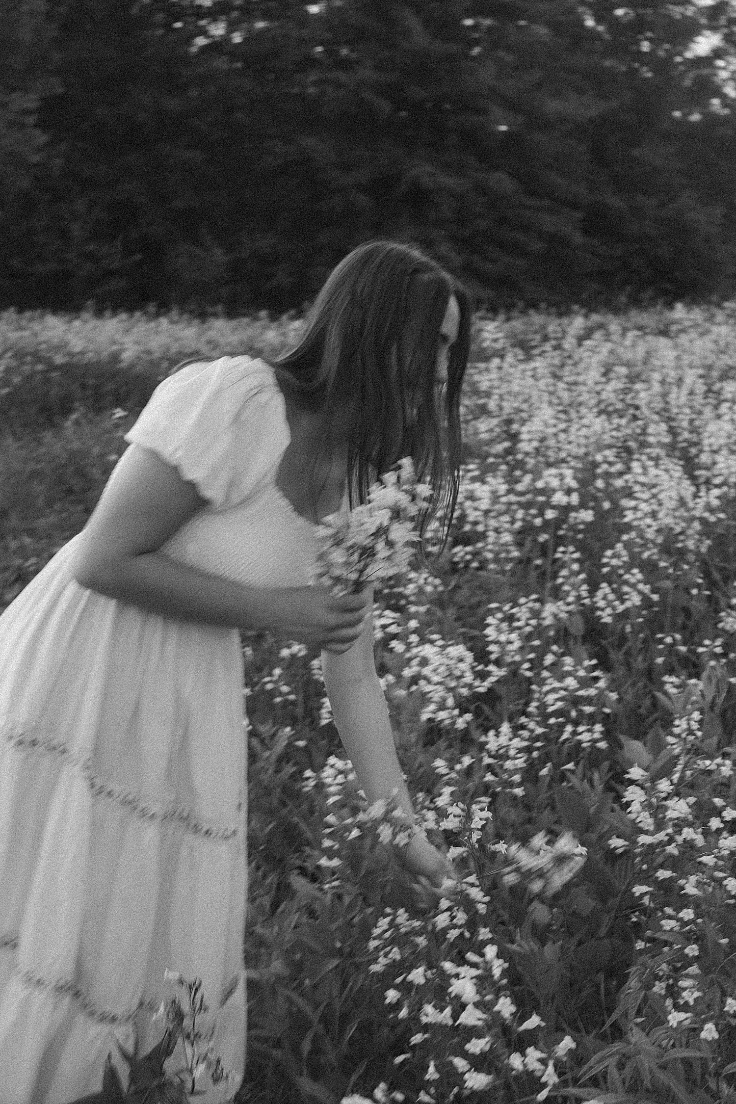 woman dips to pick up white flowers by St. Louis wedding photographer 