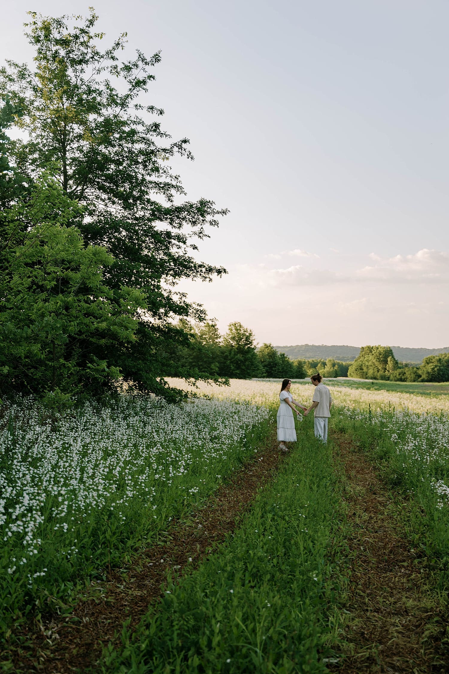 couple walk down worn path in field by Camille Meers Photography