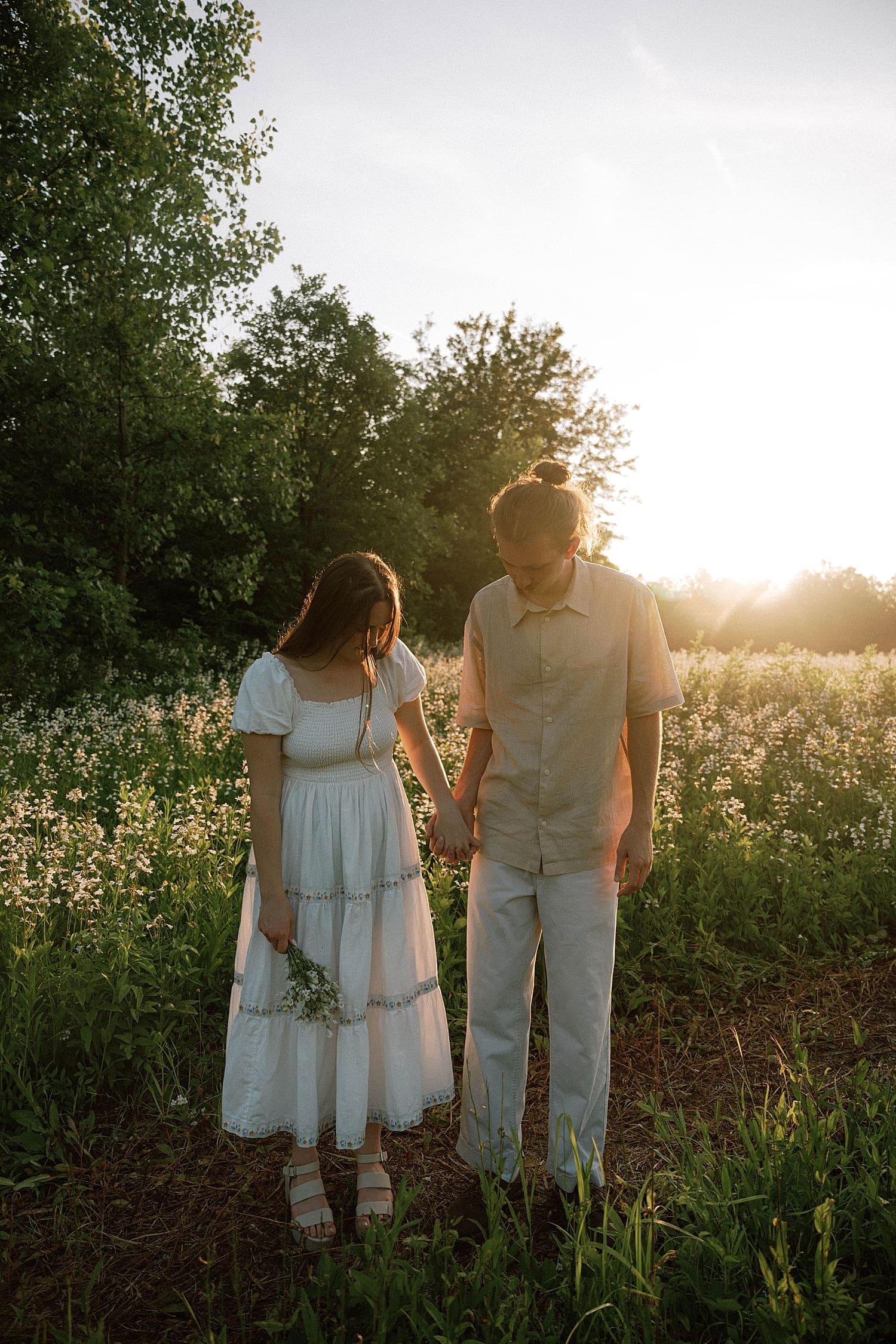 couple holds hands in golden hour lighting by St. Louis wedding photographer 