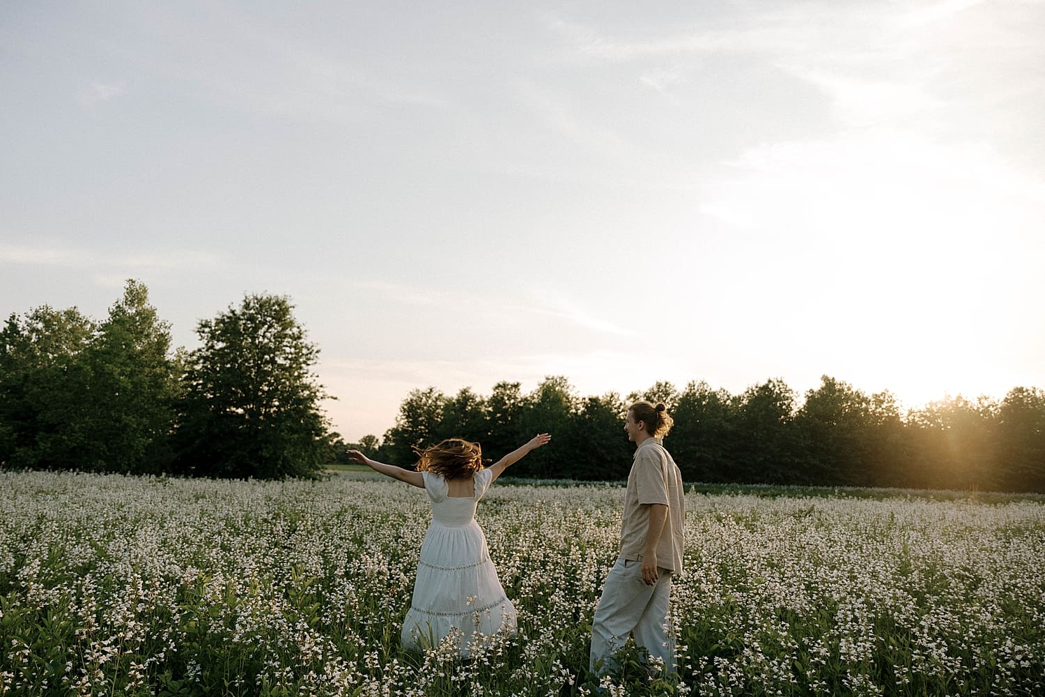 woman in white dress twirls in flowers during best time for Spring engagement photos