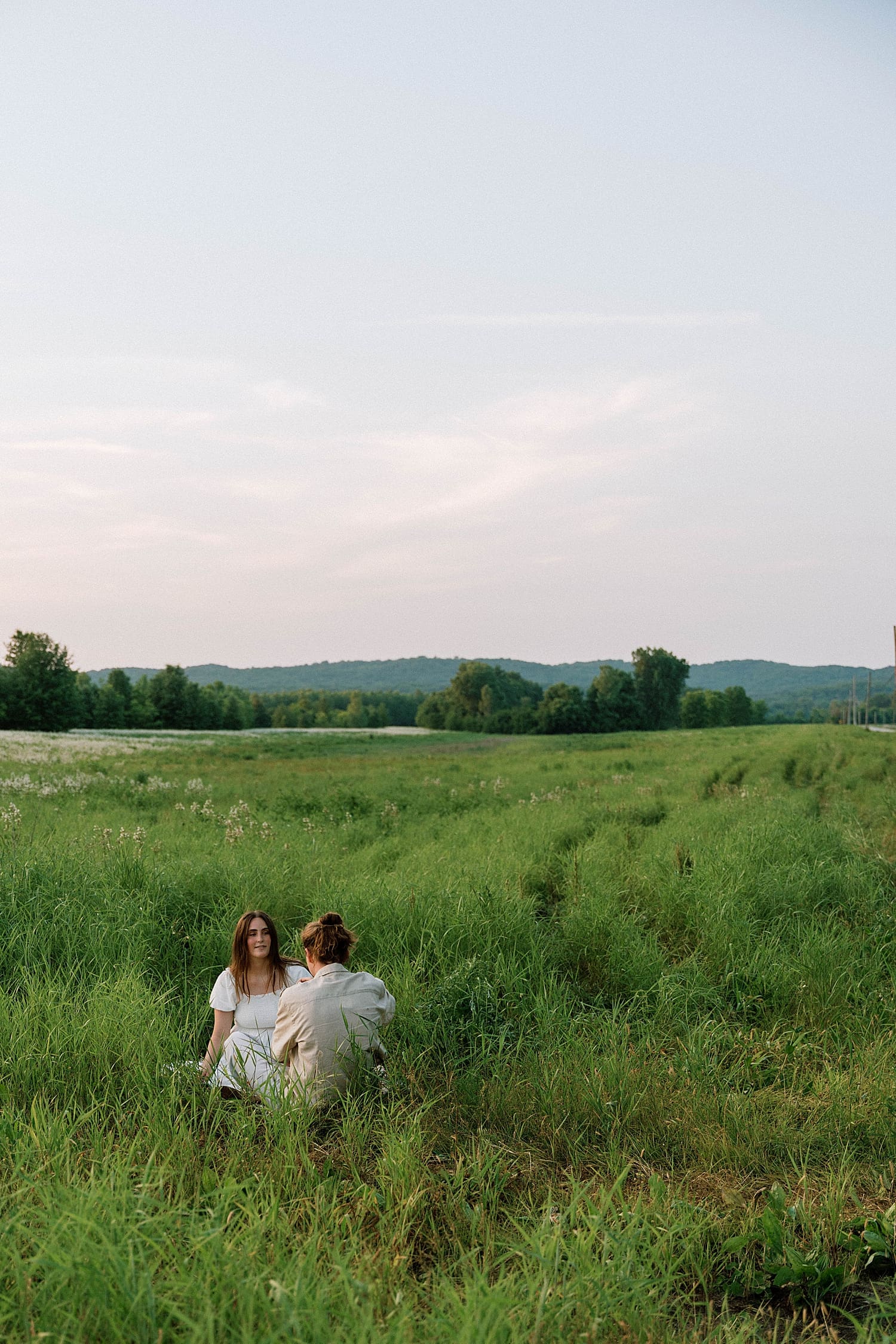 couple sits in green grass together by Camille Meers Photography