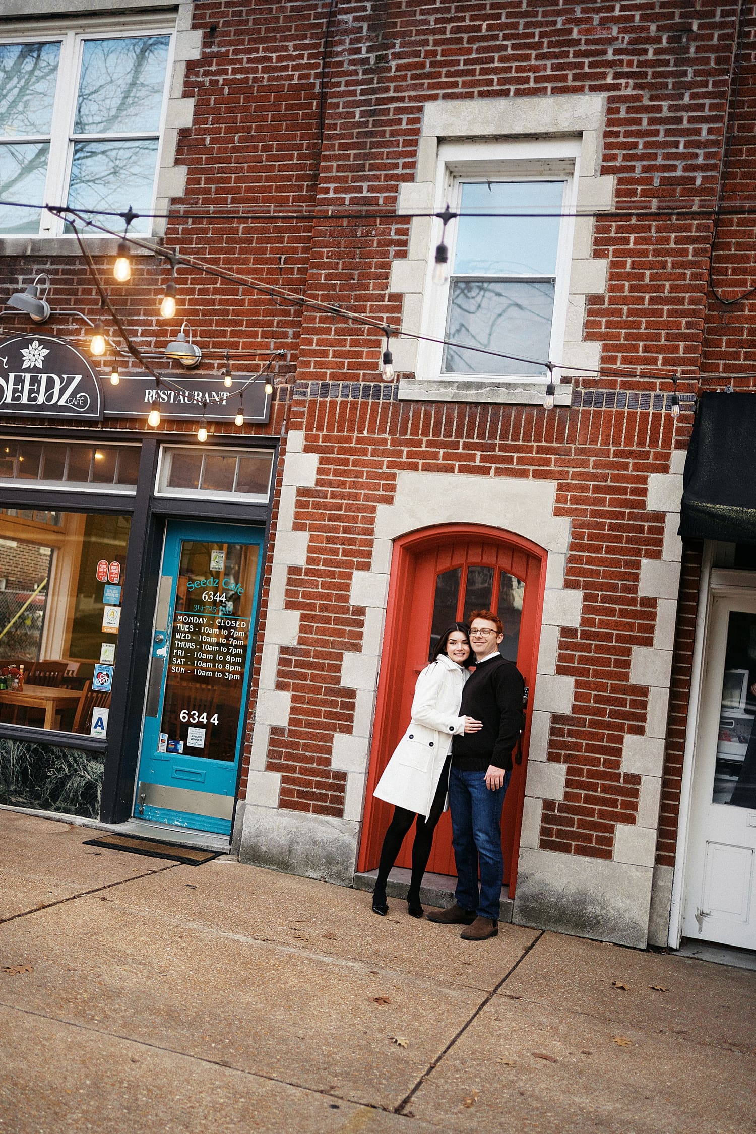 couple hugs in front of red door showing your engagement session should happen where you live