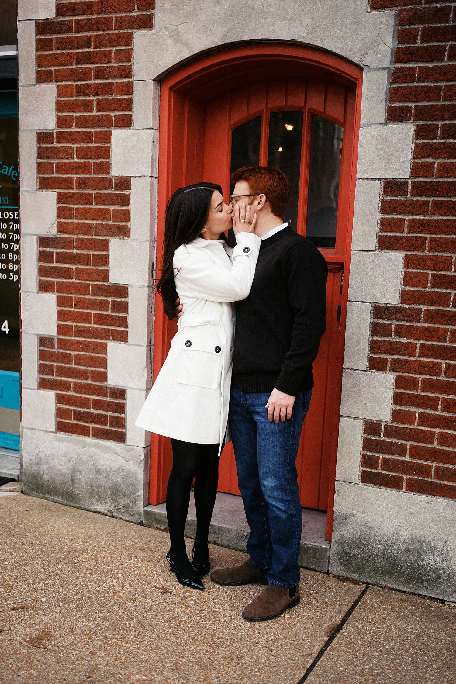 engaged couple kisses in front of red door by St. Louis Wedding Photographer