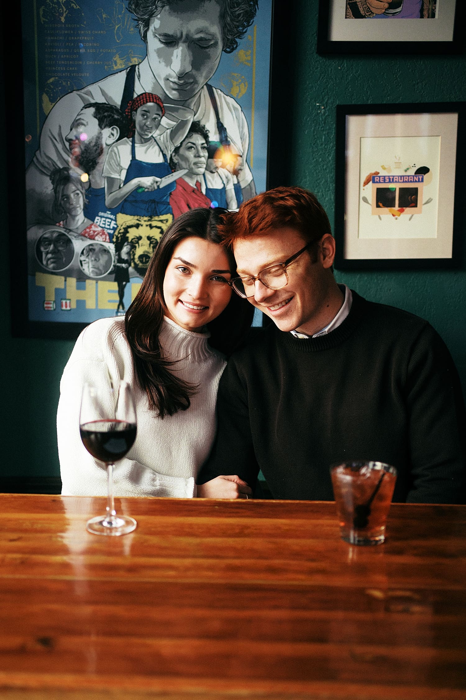 woman and man sit close together at hightop table showing your engagement session should happen where you live