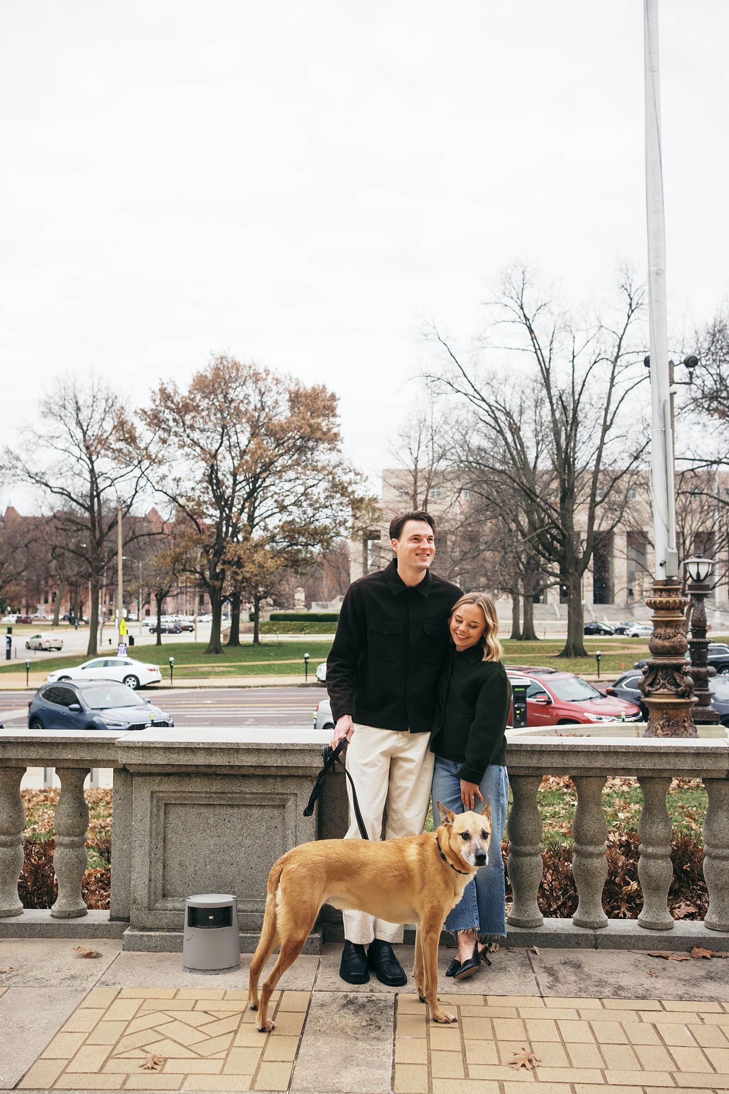 man and woman hold dog's leash on sidewalk by Camille Meers Photography