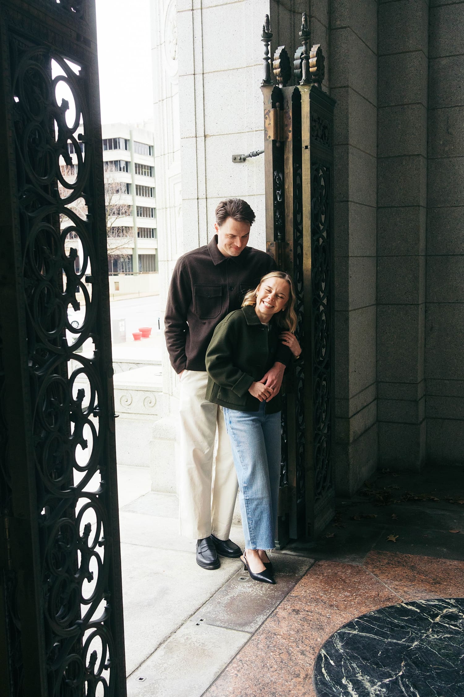 man and woman snuggle in doorway after learning how to feel natural in engagement photos