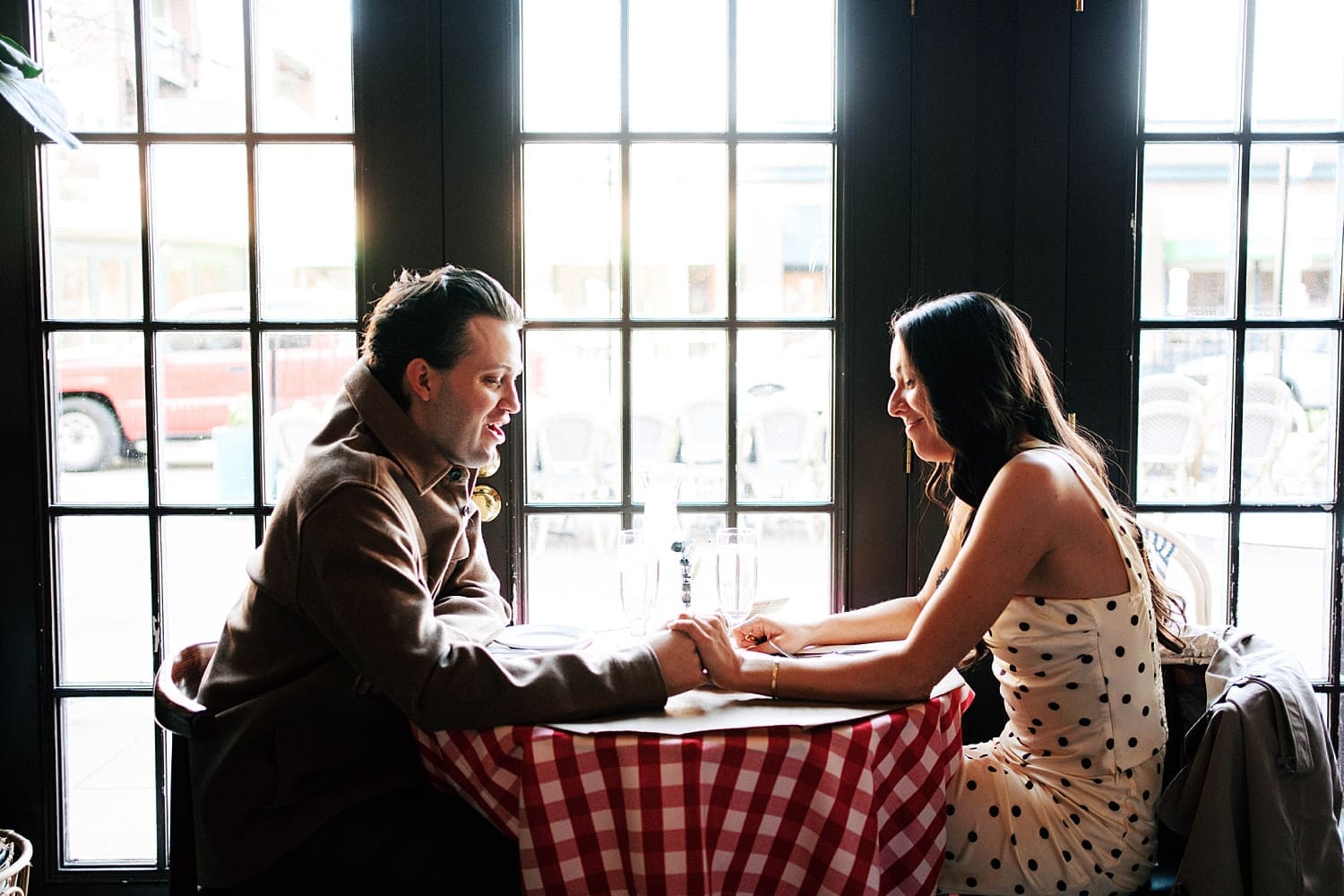 couple embrace over red checkered table for photos that feel like date night