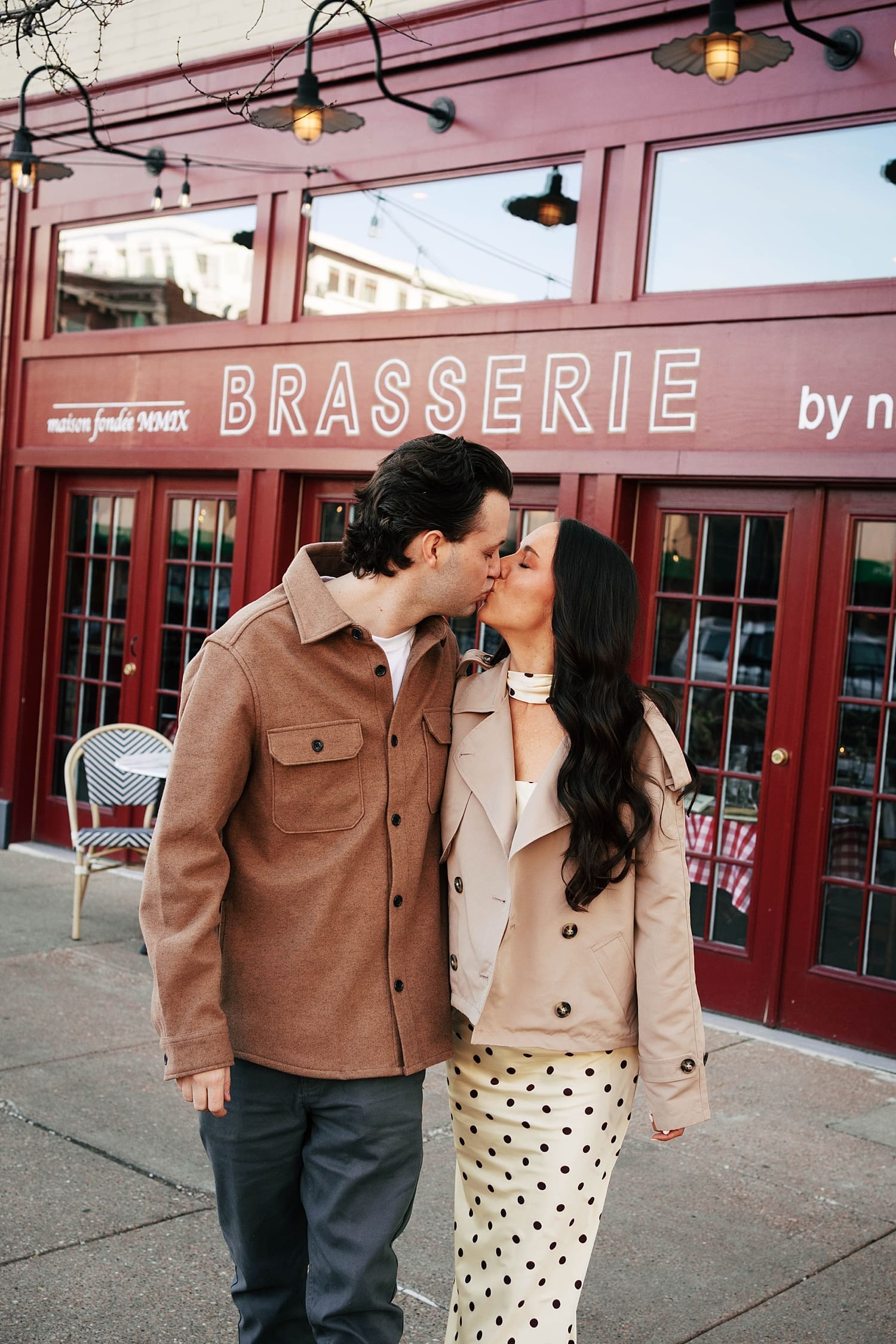 brunette couple walk in their jackets in front of restaurant for photos that feel like date night