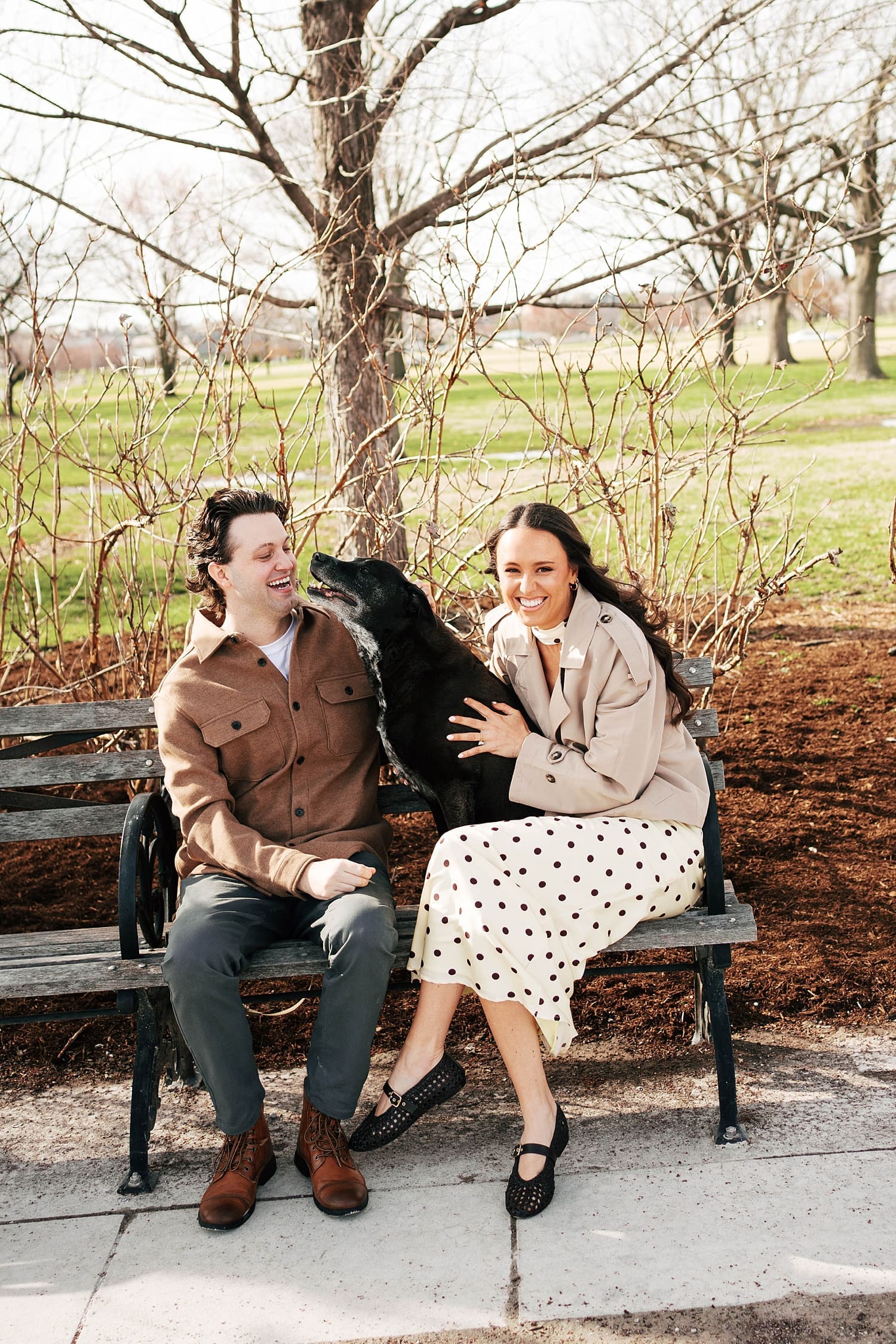 two people sit with their dog on Forest Park bench for photos that feel like date night