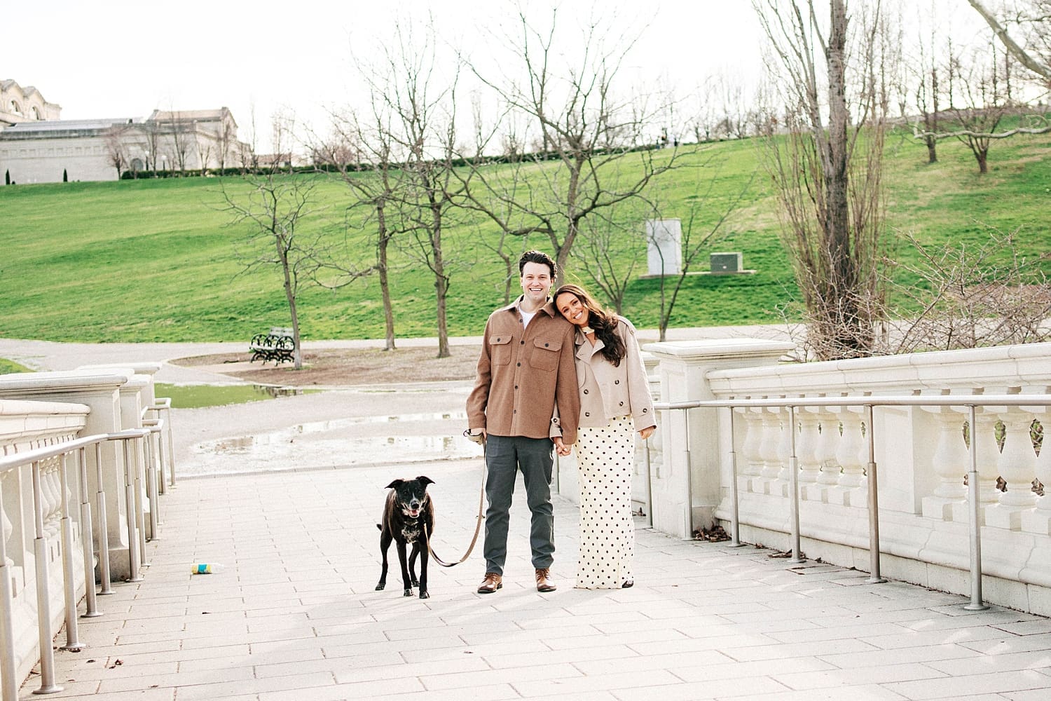 engaged couple stand on bridge with their dog for photos that feel like date night