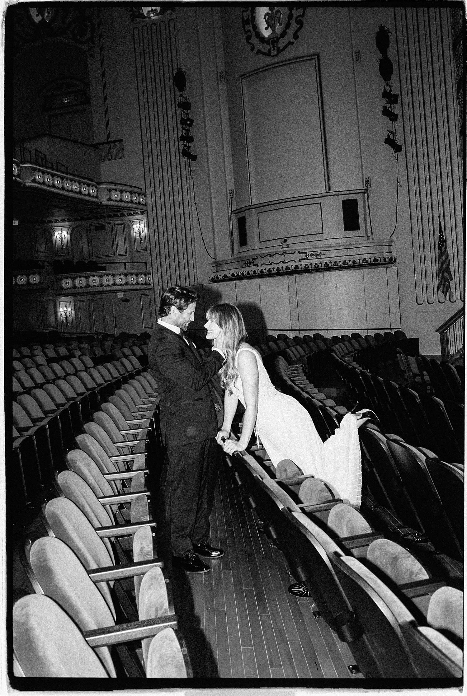 cute couple lean over chairs in auditorium in Powell Hall
