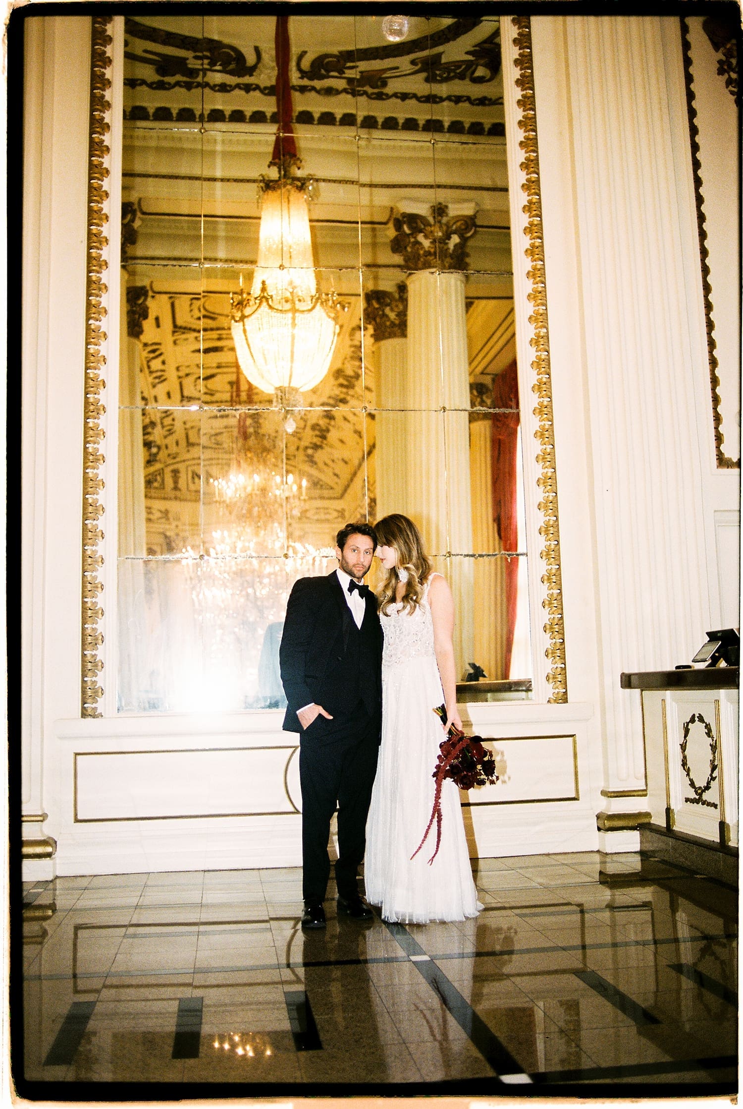 newlyweds lean in close in front of mirror wall by Camille Meers Photography