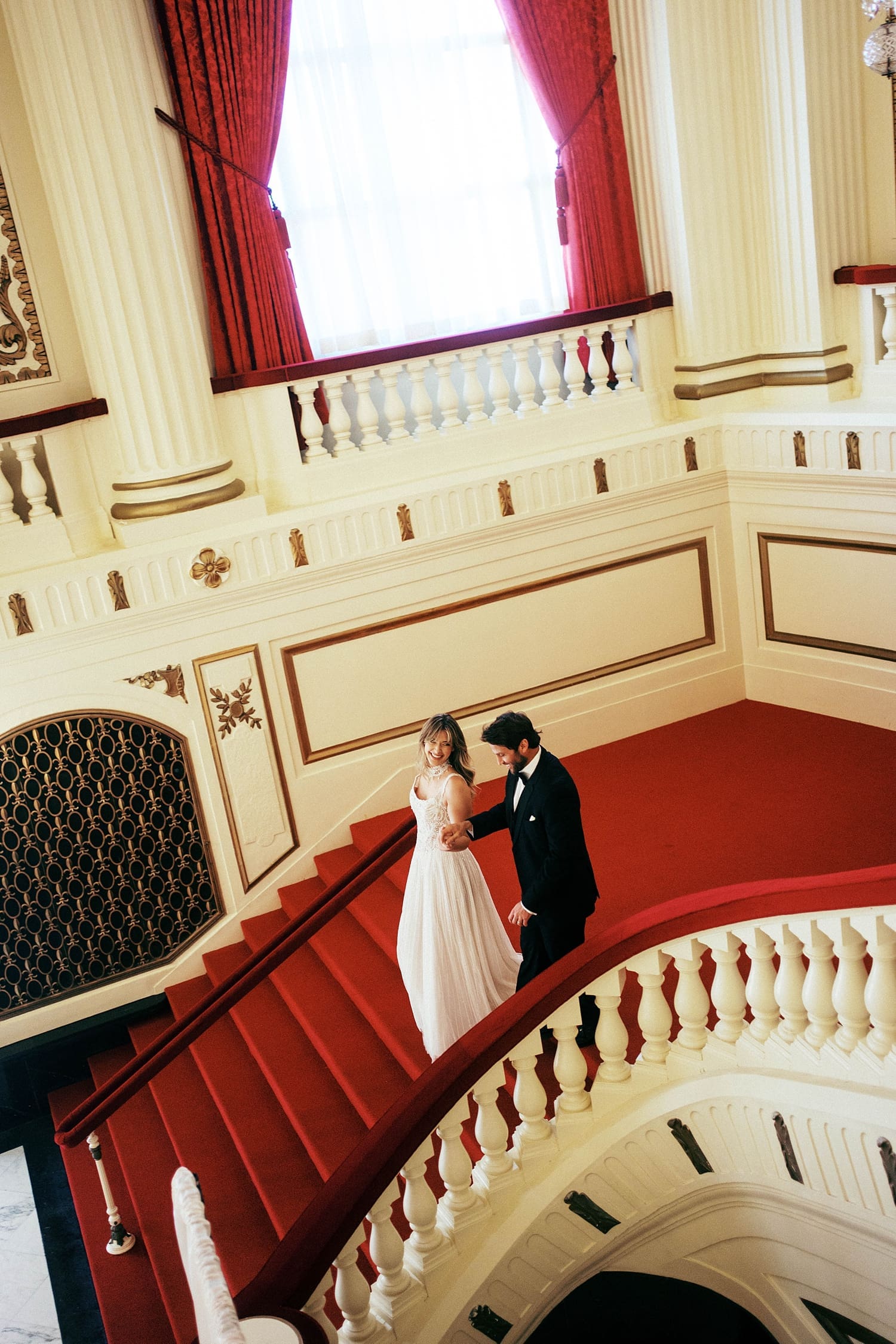 husband and wife walk down sweeping staircase by Camille Meers Photography