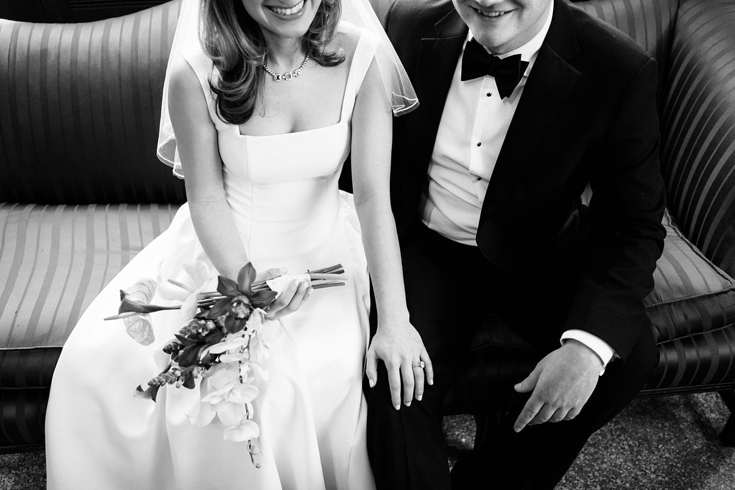 newlyweds smile and sit together on a couch by St. Louis Wedding Photographer