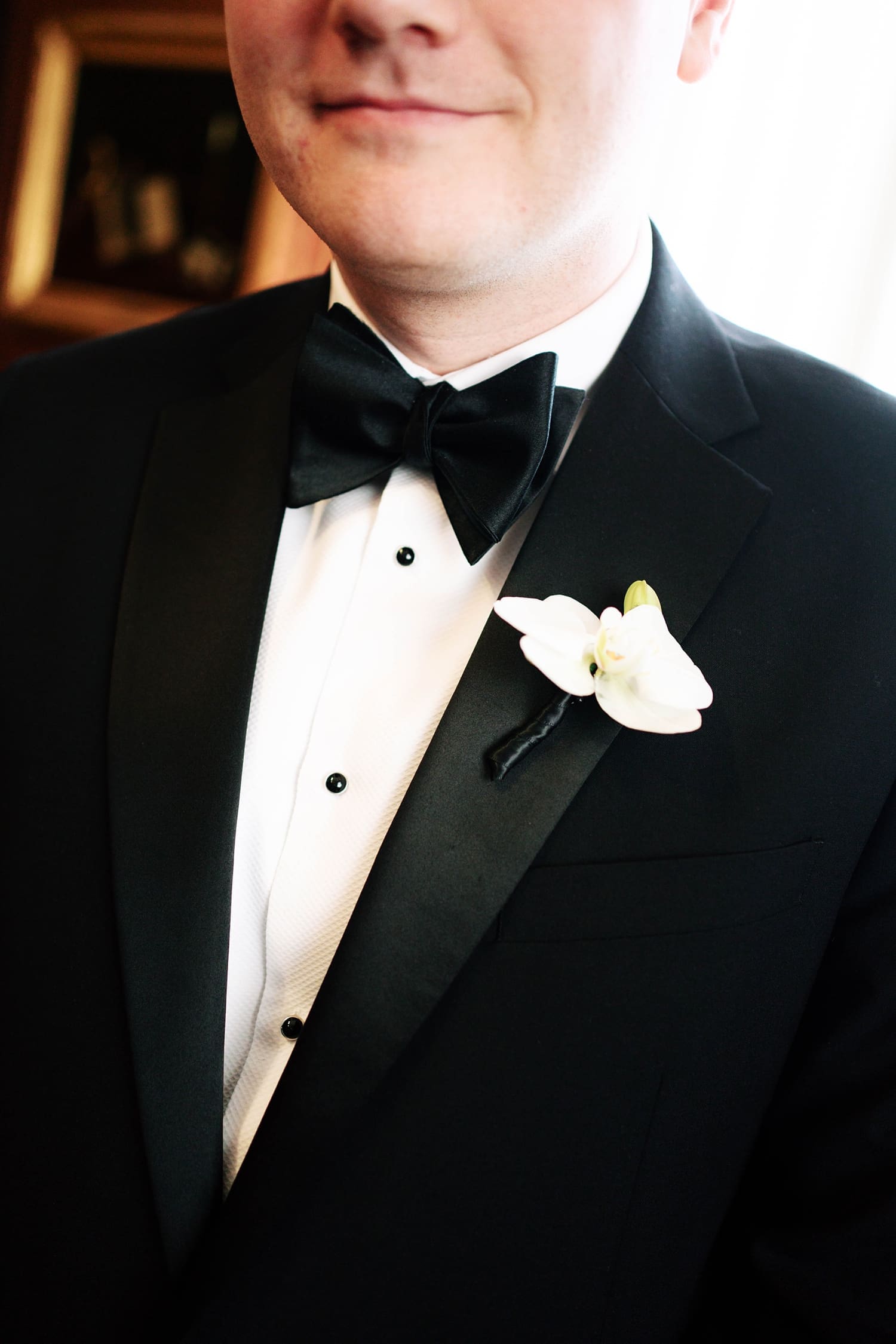 groom with white flower in his suit in front of window at the Missouri Athletic Club