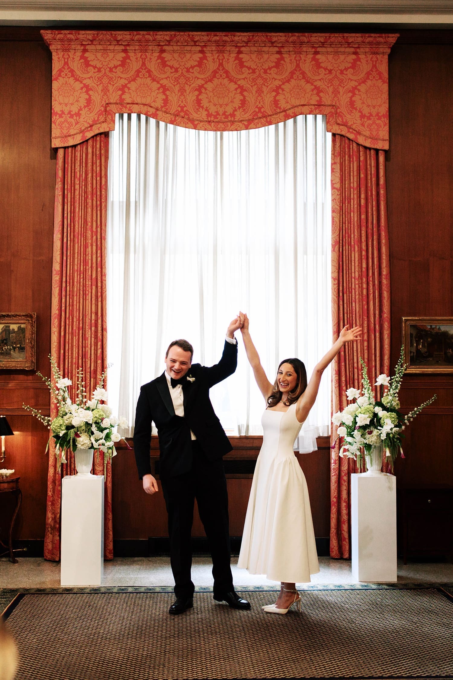 newlywesd throw their hands in the air in celebration at the Missouri Athletic Club