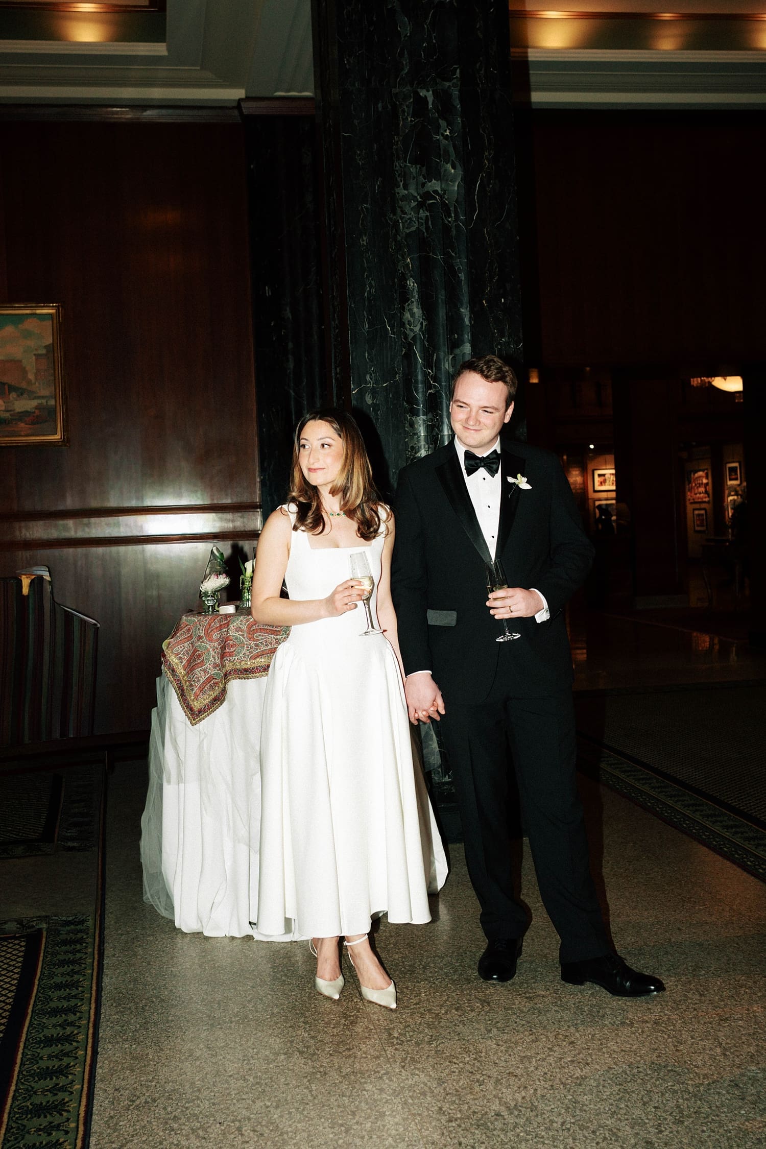 husband and wife hold glasses for formal toasts by St. Louis Wedding Photographer