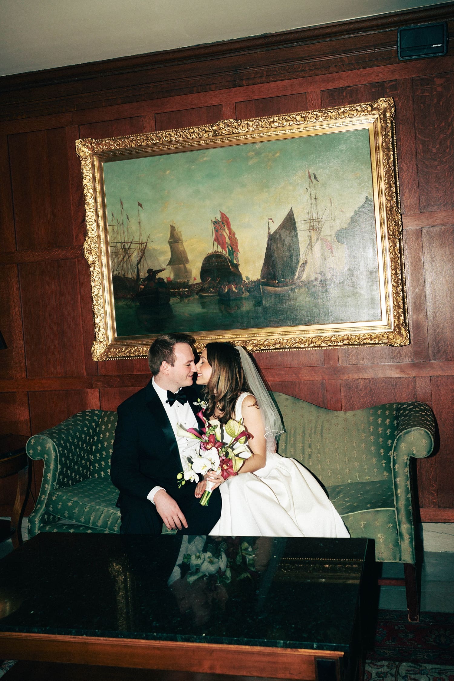 newlyweds share a kiss on vintage couch by St. Louis Wedding Photographer