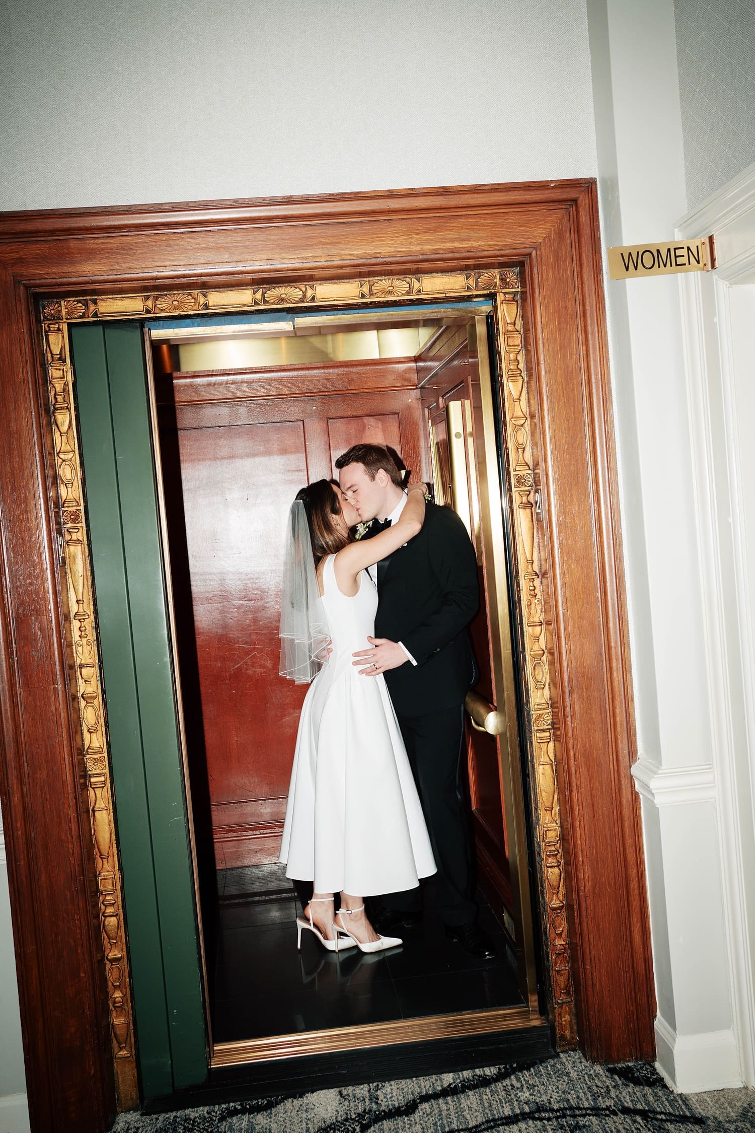 newlyweds share a kiss in an elevator at the Missouri Athletic Club