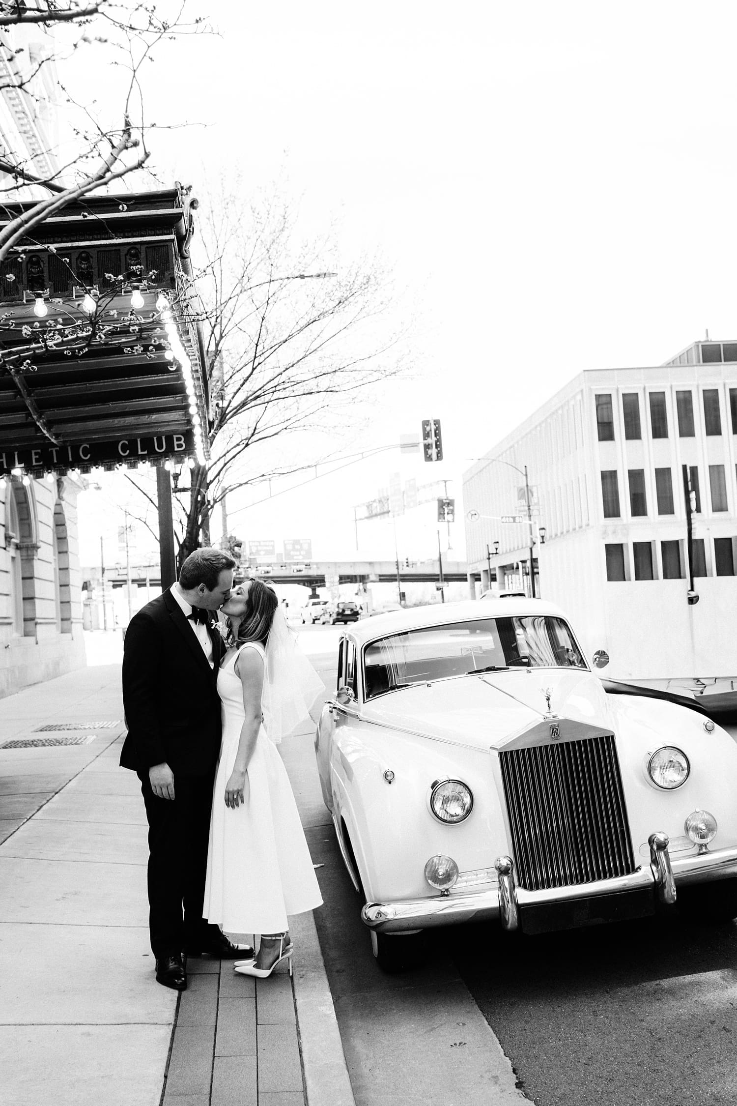 couple share a kiss while standing next to rolls royce by St. Louis Wedding Photographer