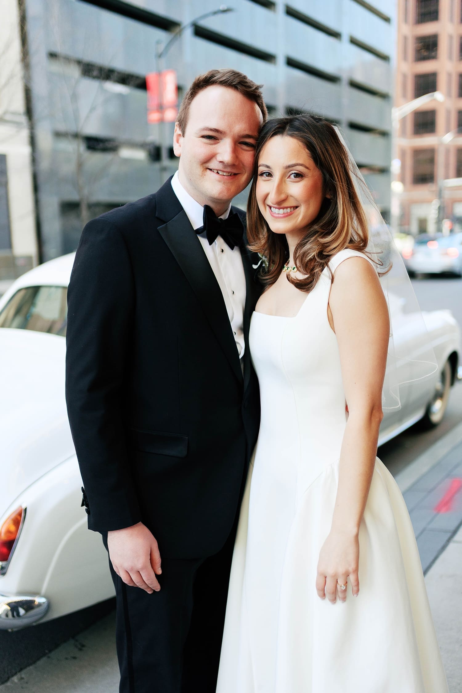 bride and groom stand on side walk in front of rolls royce at the Missouri Athletic Club