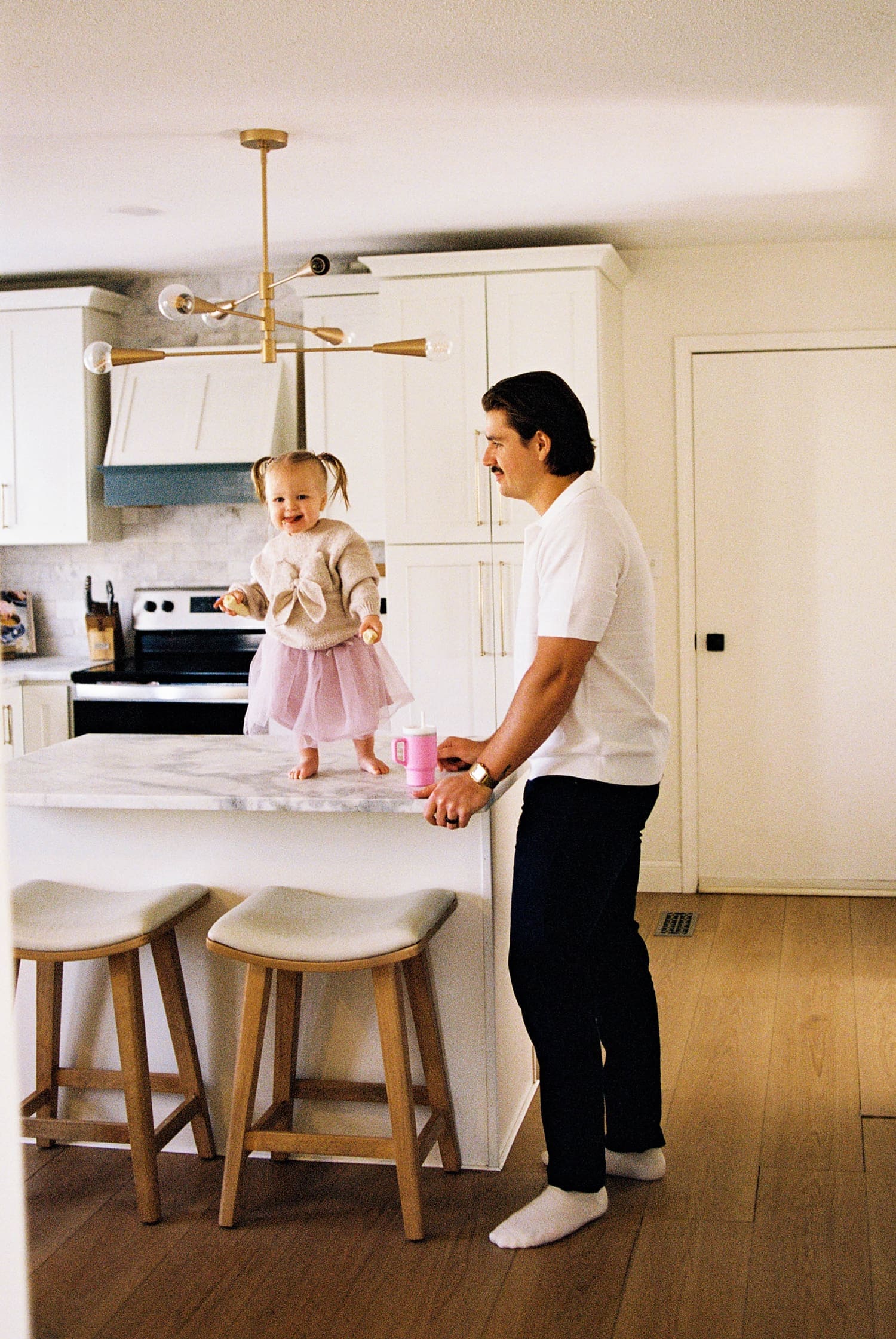 daughter dances on kitchen island next to her father by Camille Meers photography