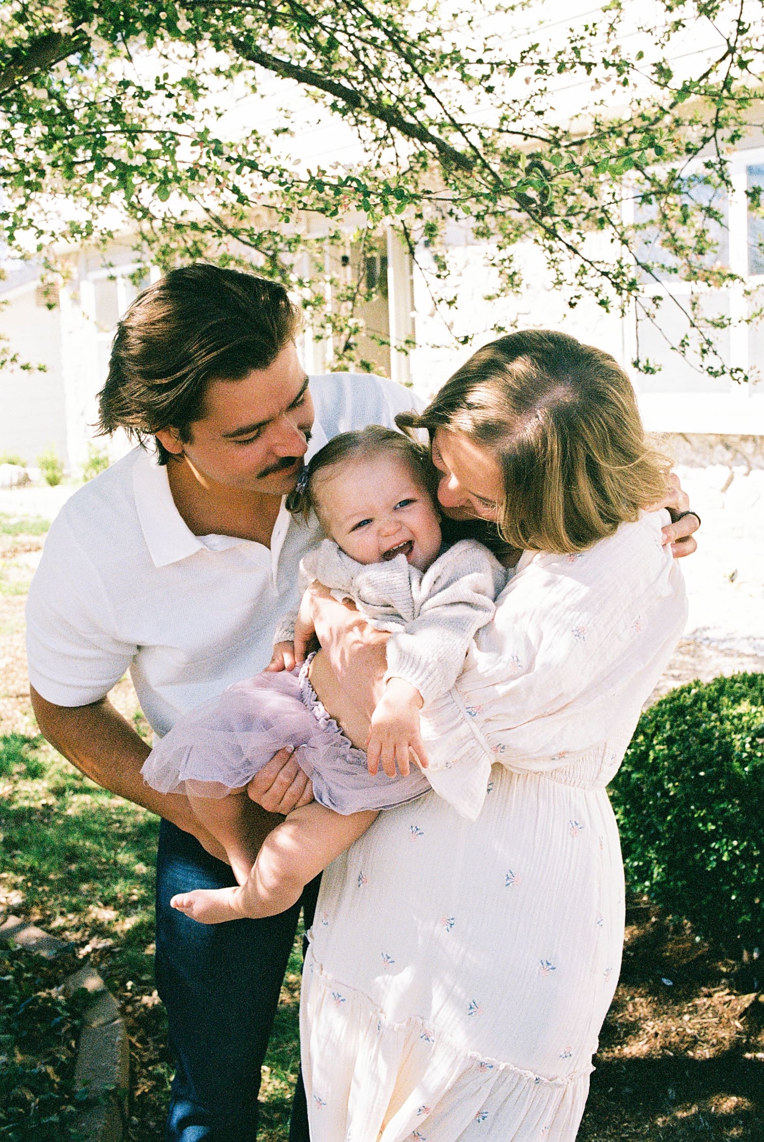 mom and dad hold their little toddler outside for relaxed family session at home