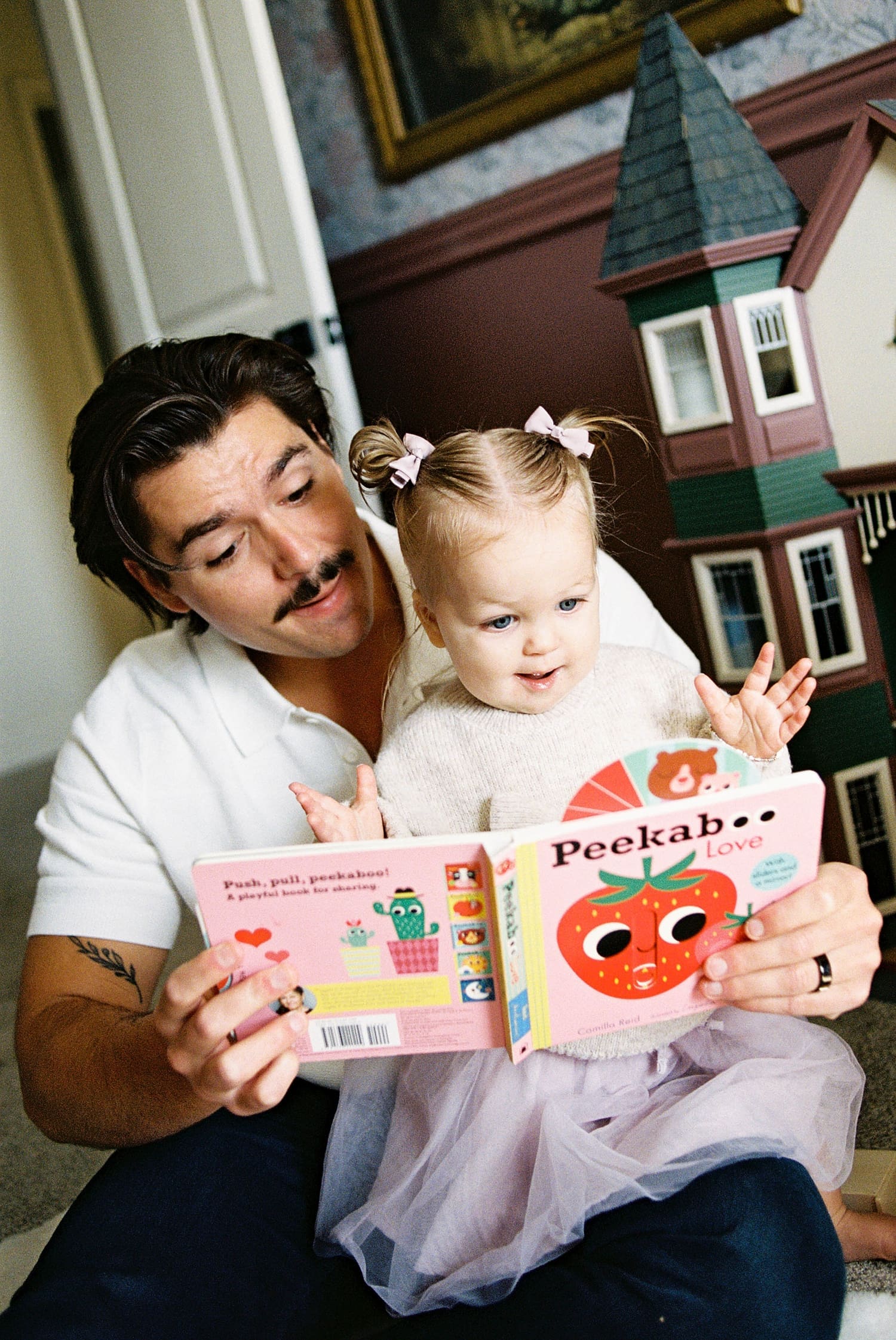 father reads a book to his daughter on the floor by St. Louis film photographer