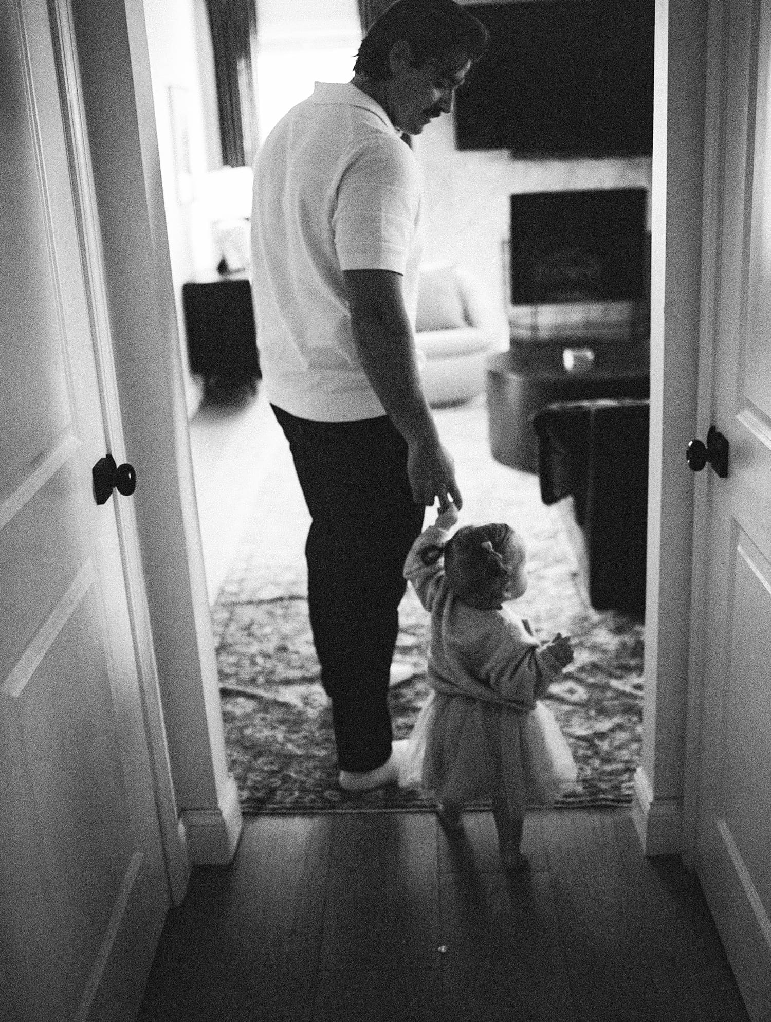 father leads his daughter through a doorway for relaxed family session at home