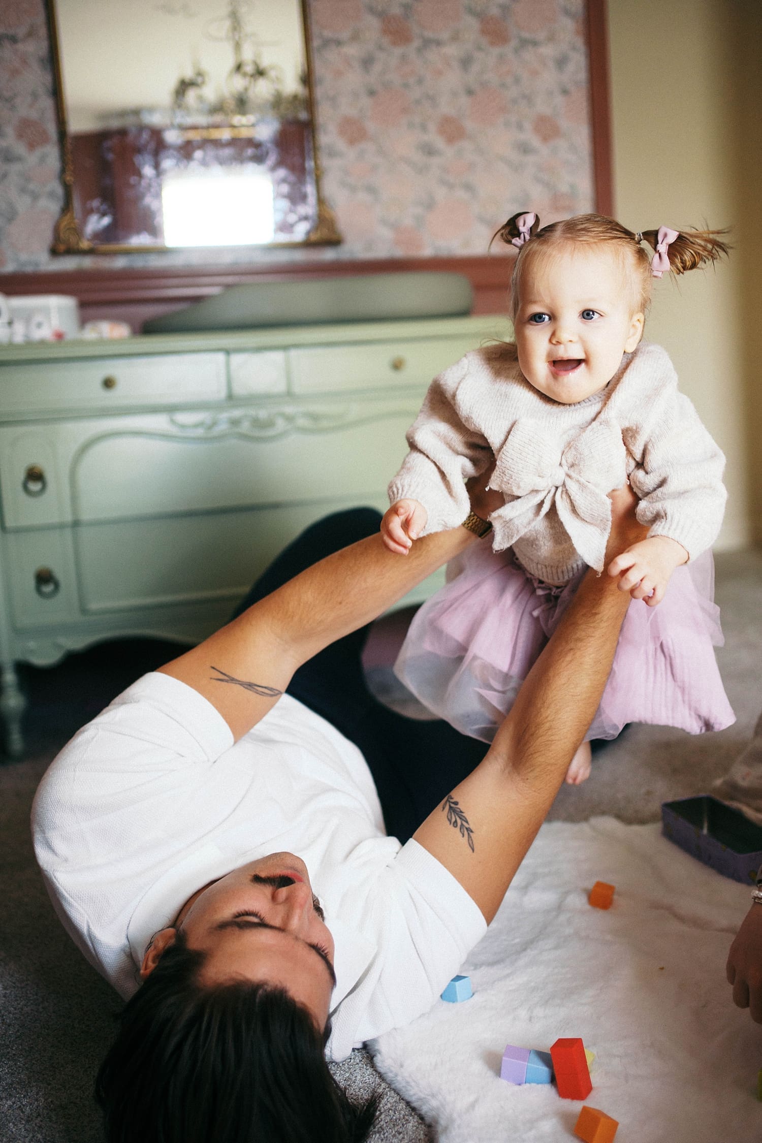 dad lies on the ground holding up one year hold by Camille Meers photography