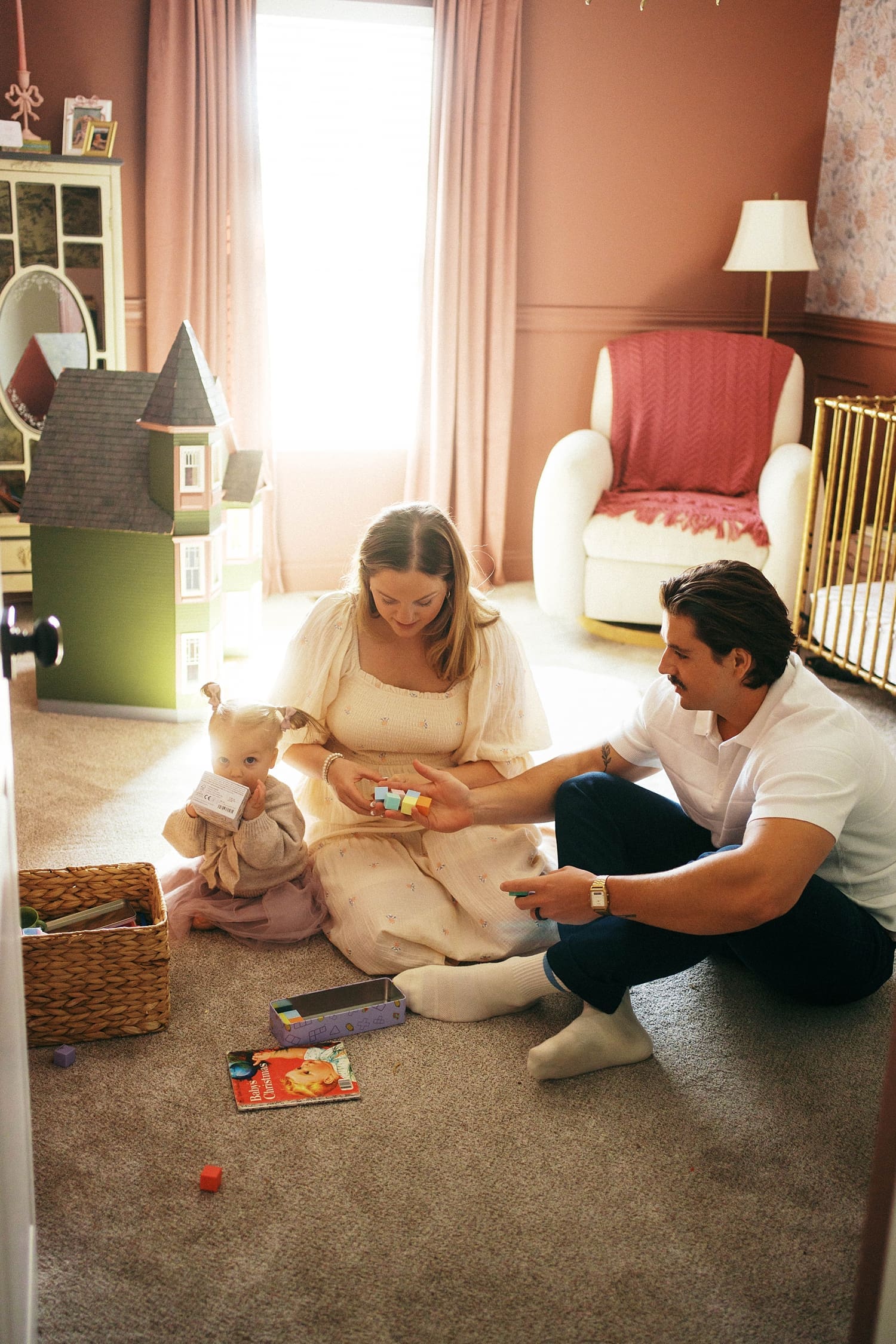 parents sit on nursery floor playing toys with kids by St. Louis film photographer