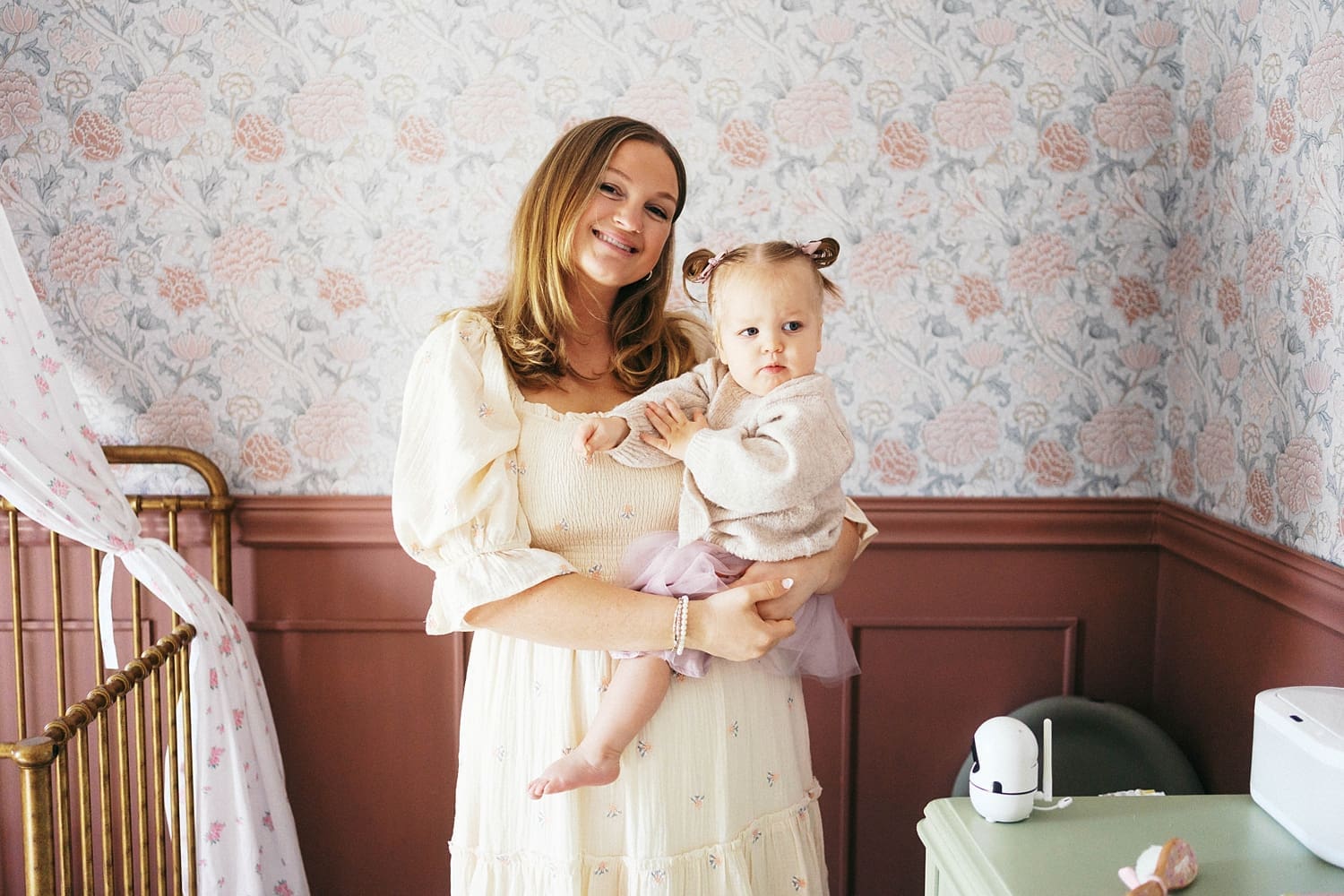 mother stands with her baby in nursery for relaxed family session at home