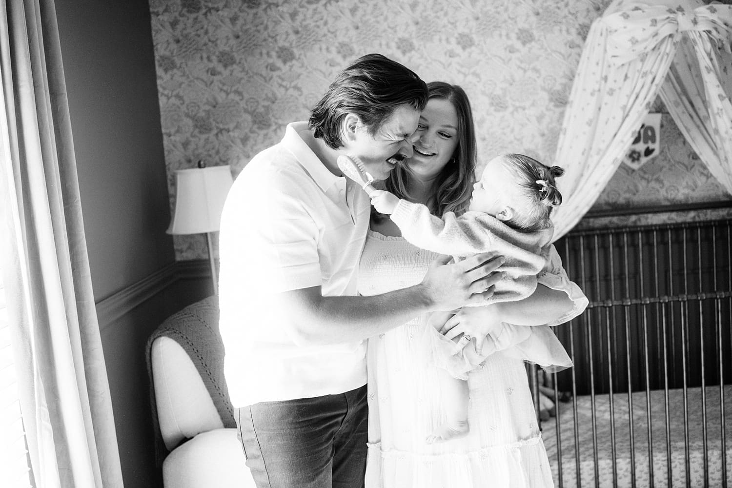 baby reaches for her father while mom holds her by St. Louis film photographer