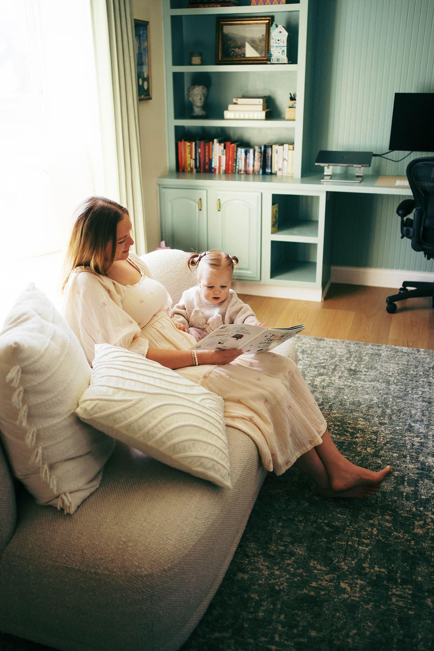 mother reads to baby on little couch by St. Louis film photographer