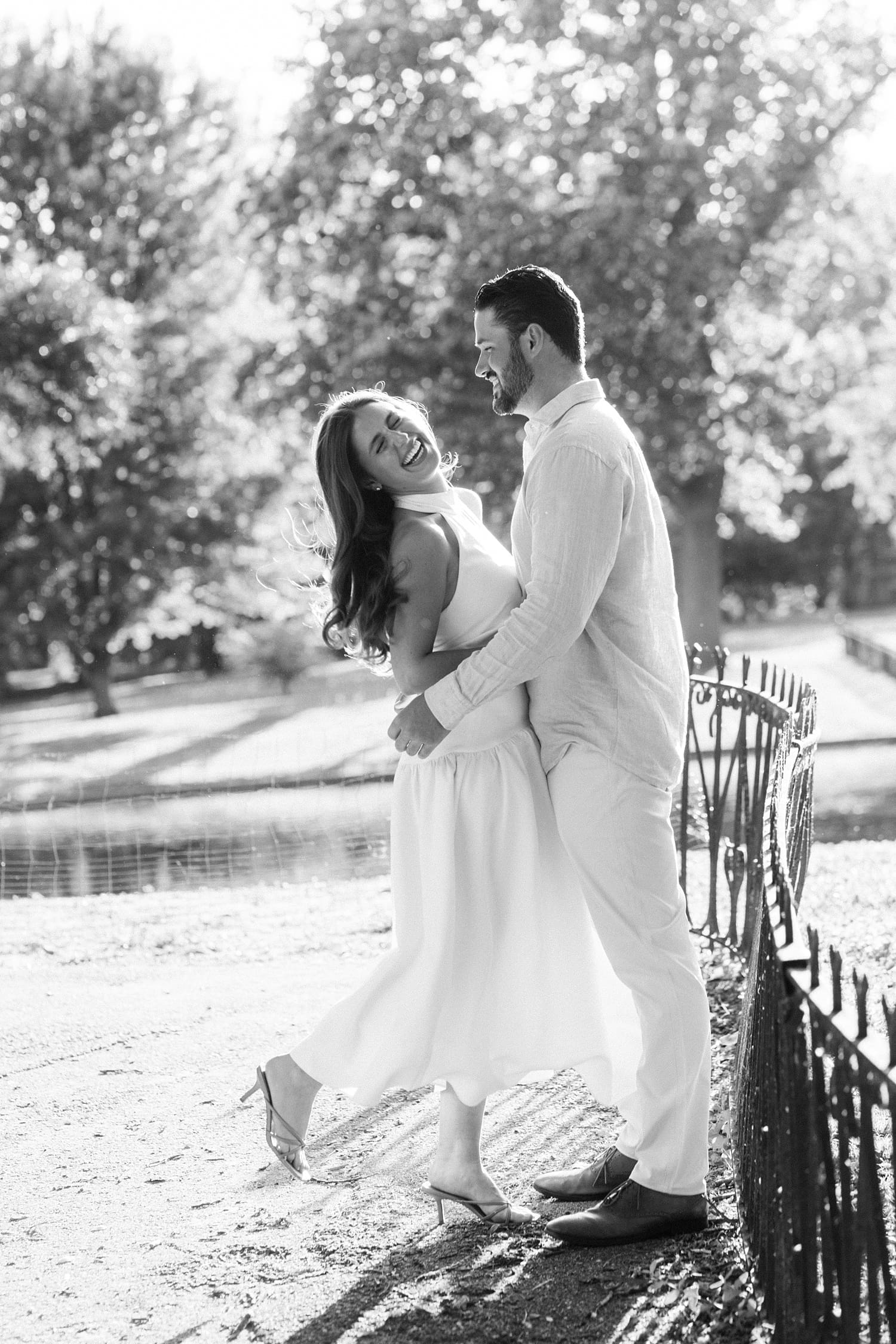 couple stands next to pond for unposed engagement session