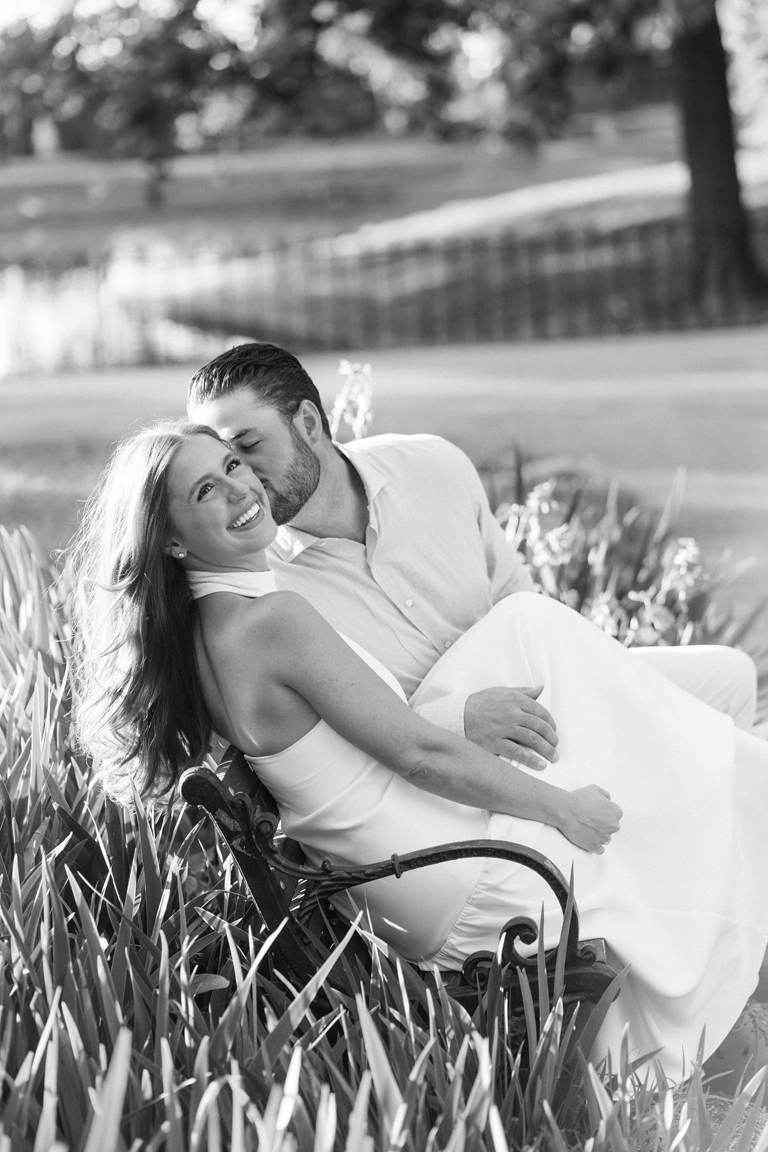 man kisses a woman's cheek on park bench by documentary wedding photographer