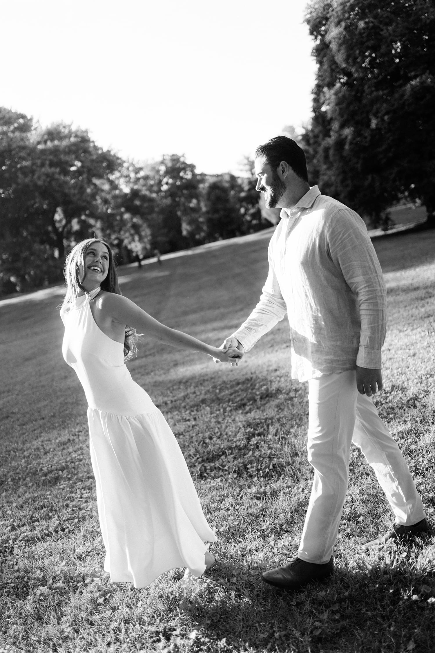 two people walk hand in hand across a field for unposed engagement session